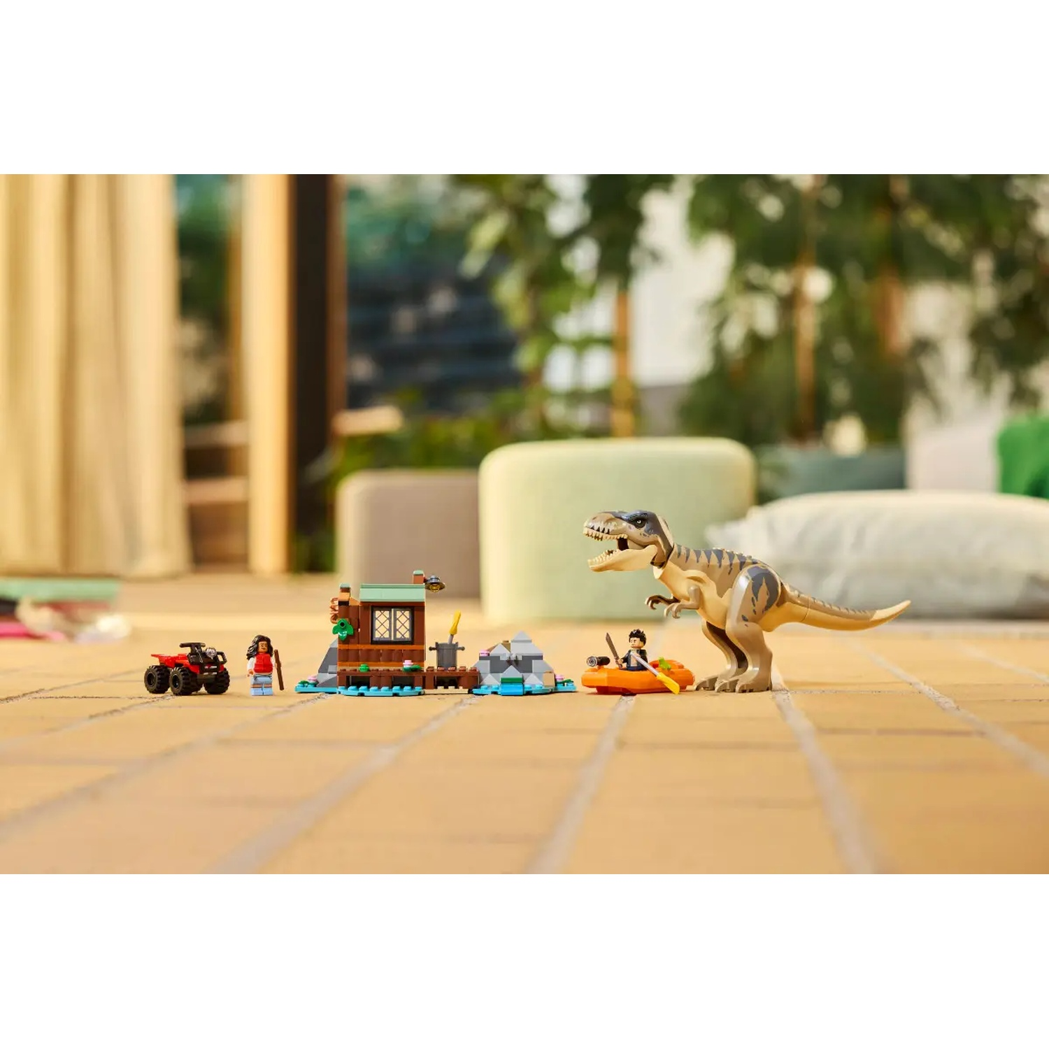 A Lego set shows a dinosaur, a boat, a house, a quad bike, and figurines on a tiled floor. Background shows greenery and a couch.