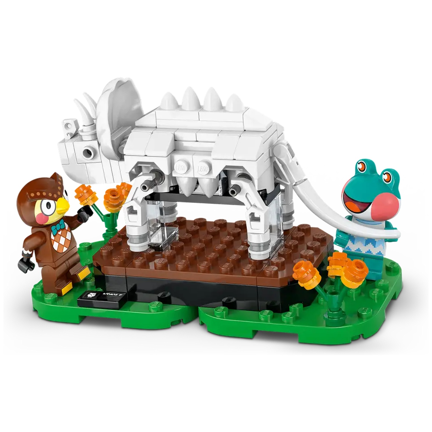 Ensemble Lego avec un squelette de dinosaure blanc, un hibou et une grenouille sur une base verte avec des fleurs oranges.