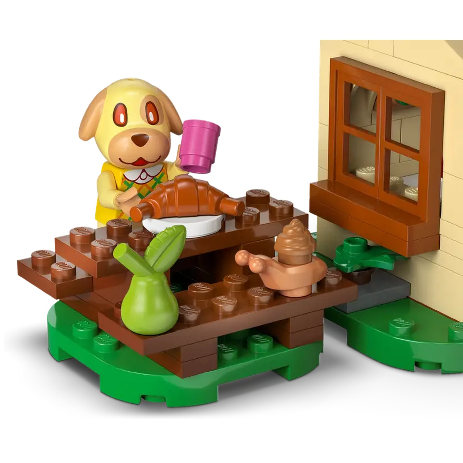 Une scène Lego montre un personnage de chien tenant une tasse rose, un croissant et une poire sur une table. Une fenêtre et un bâtiment sont également visibles.