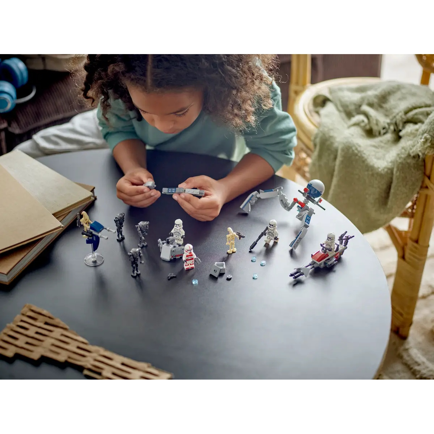 Een kind speelt met Star Wars Lego op een zwarte tafel. Lego-personages en voertuigen zijn geassembleerd.
