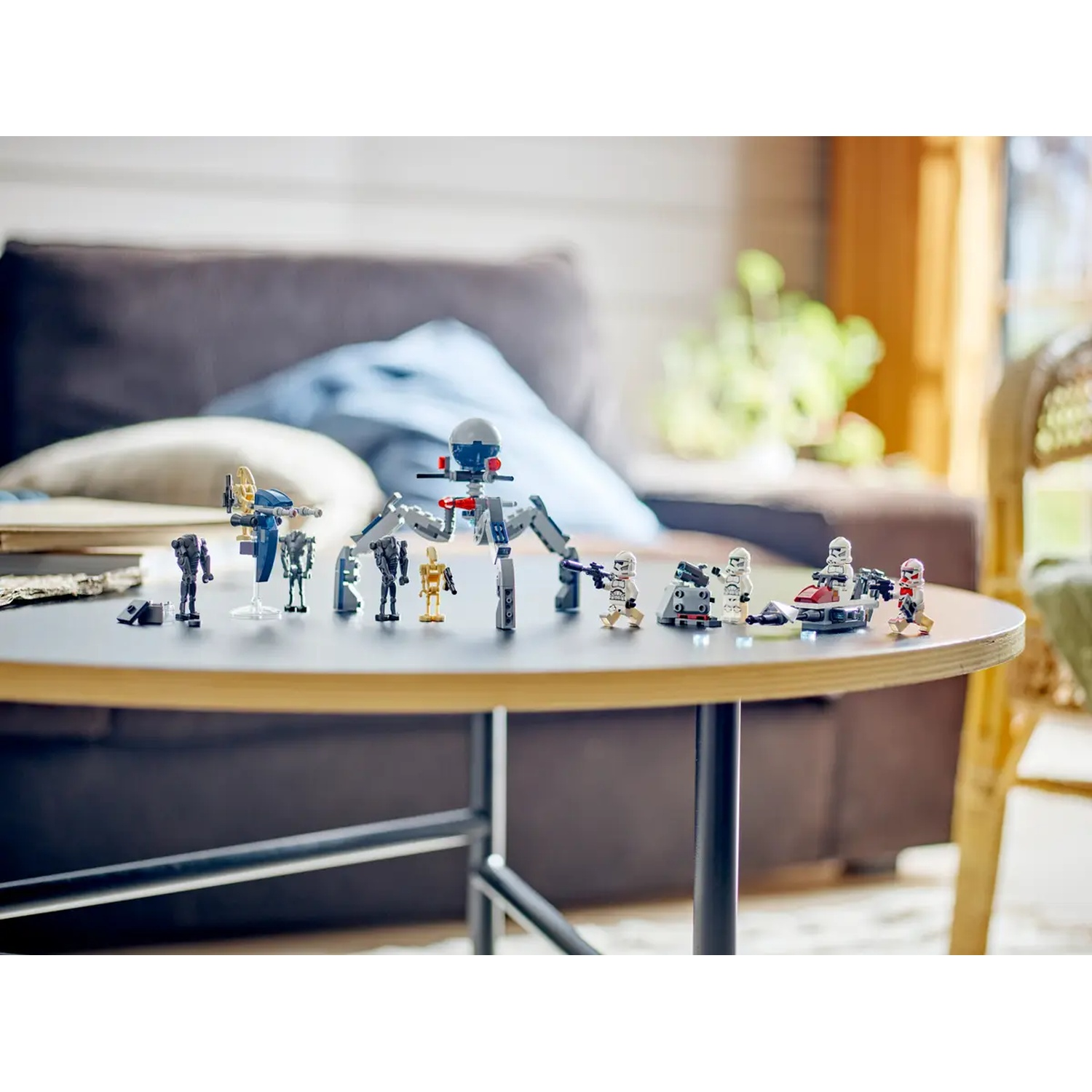 Lego Star Wars-figuren op een tafel. Inclusief verschillende personages, een droid en voertuigen. De achtergrond toont een bank en een raam.