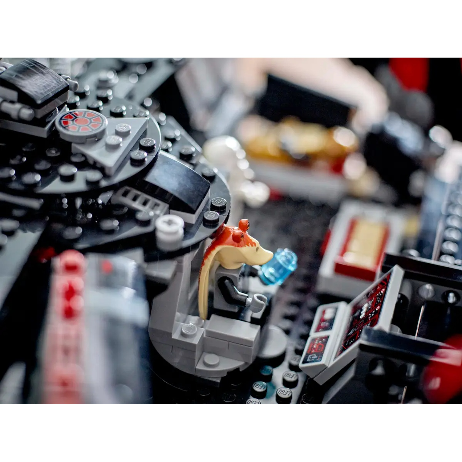 A Lego Star Wars scene features Jar Jar Binks in a cockpit, holding a blue object. The cockpit is surrounded by gray Lego pieces.