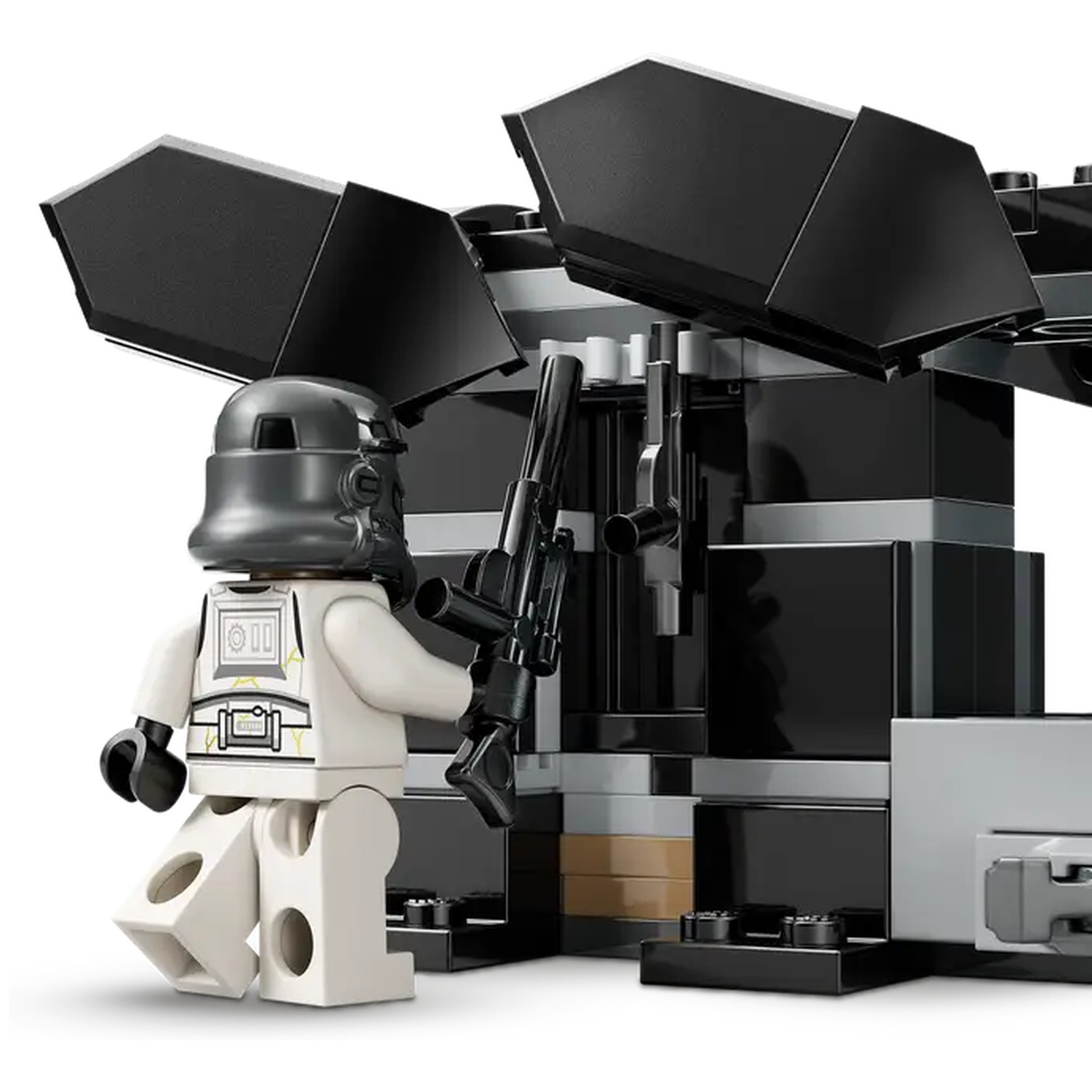 A Lego figure of a Stormtrooper holding a black gun stands near a black structure. The background is white.