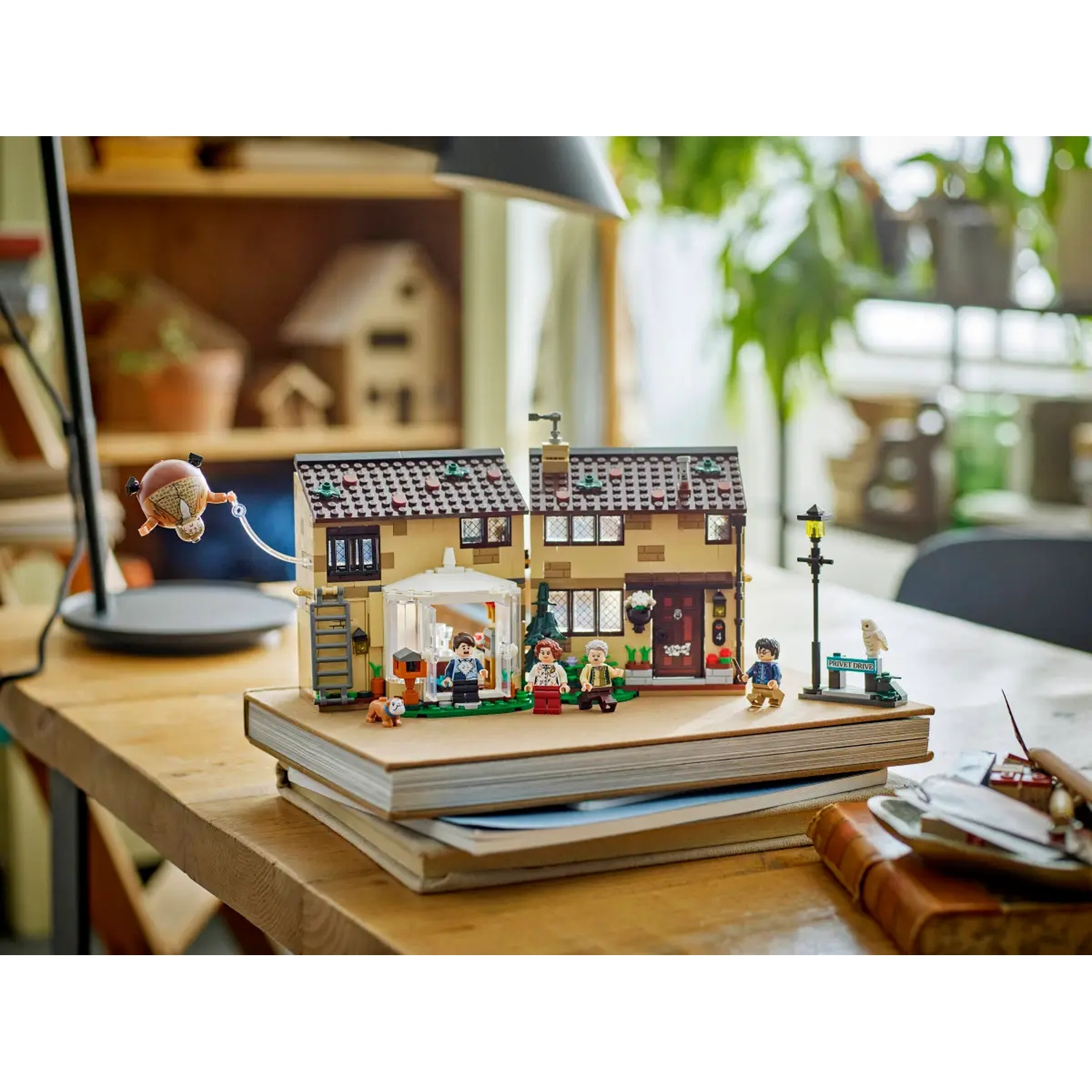 Lego set of a house on a table. Includes mini figures, a dog, and a street light. A flying object is in the air.