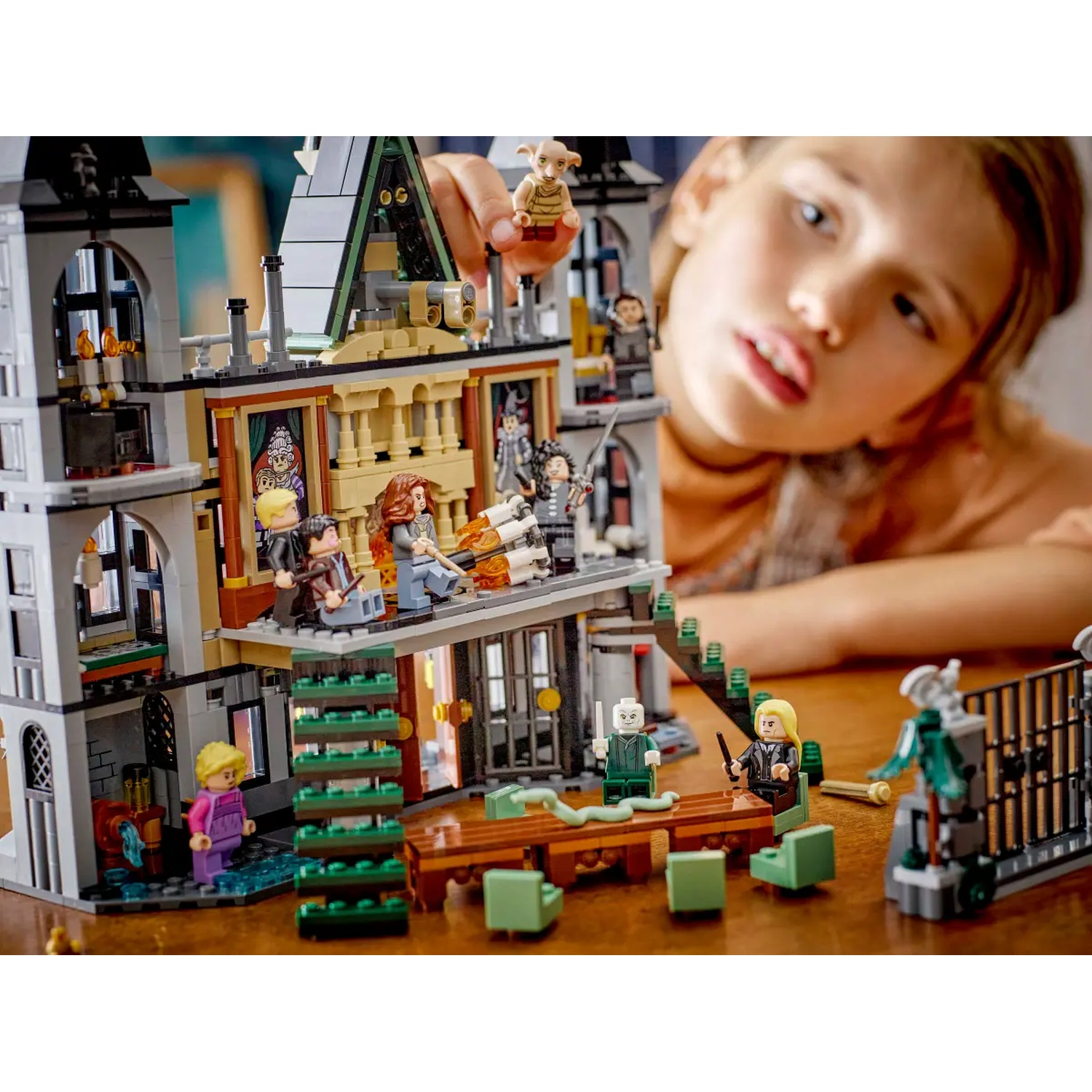 A child playing with a Lego Harry Potter set. The set depicts a castle with figures and a child looking on.