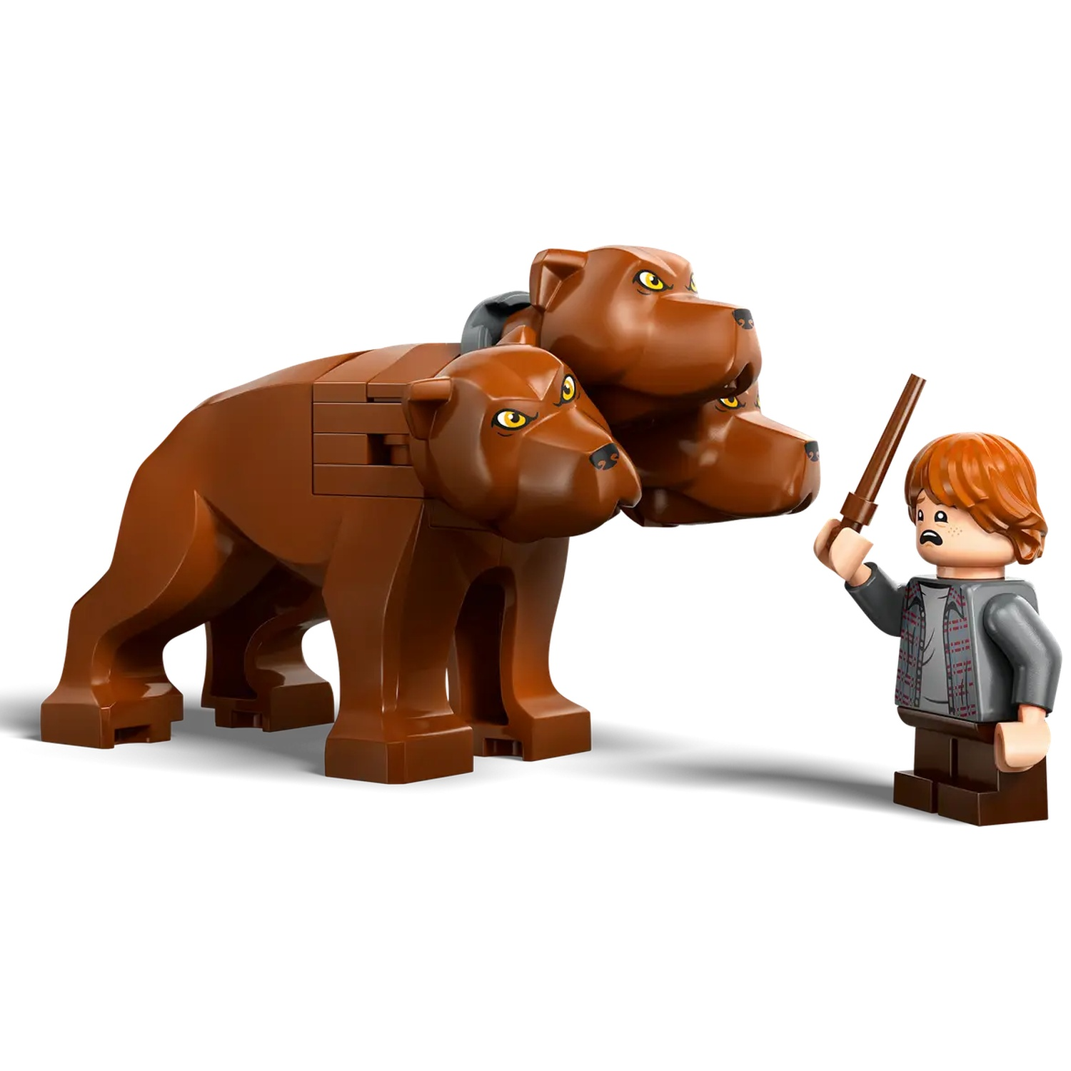Een Lego-figuur van Ron Weasley staat tegenover een bruine hond met drie koppen. Ron houdt een toverstaf vast.