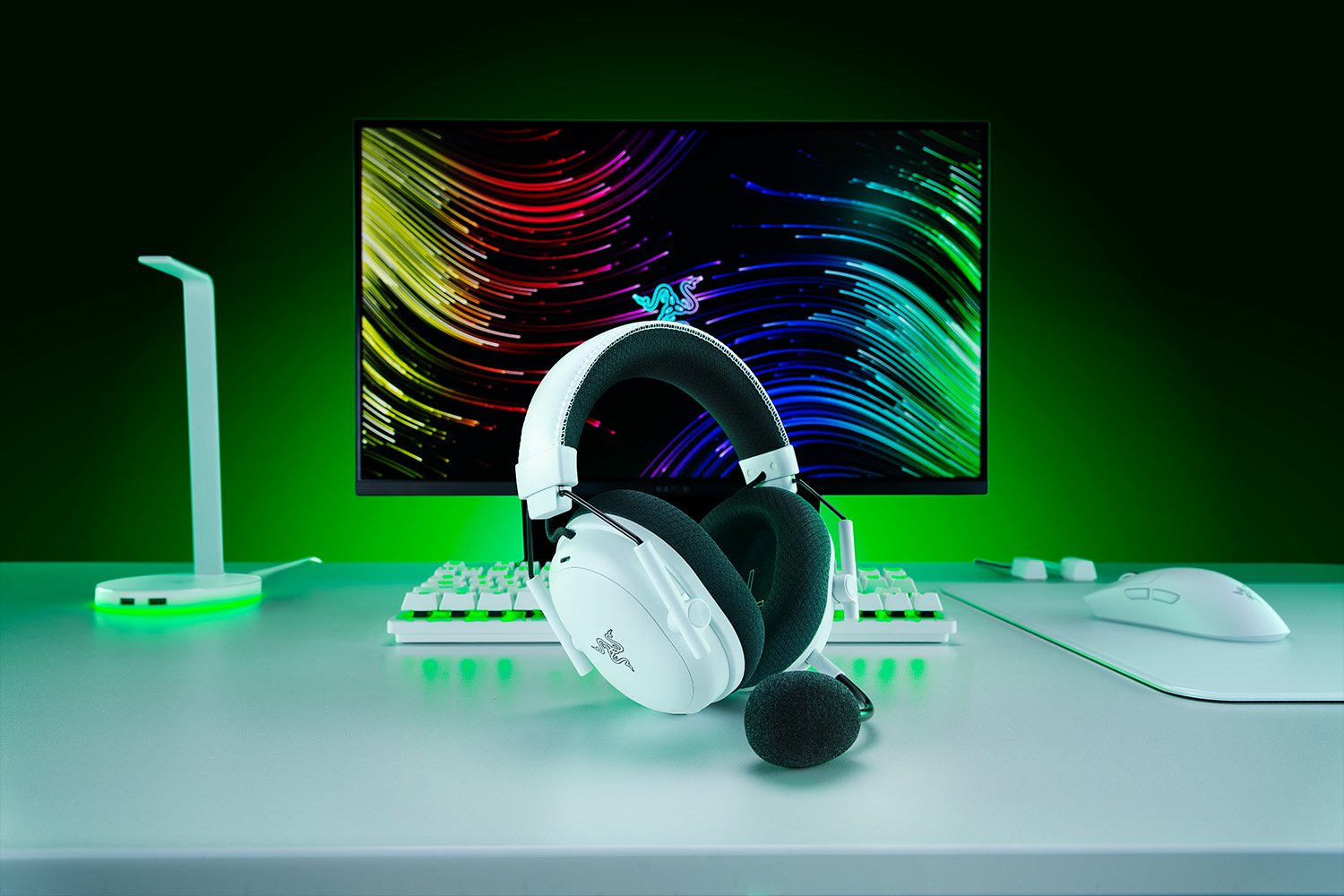 Weißes Gaming-Headset auf einem Schreibtisch mit Tastatur, Maus und Monitor mit bunten Linien. Grüner Hintergrund.