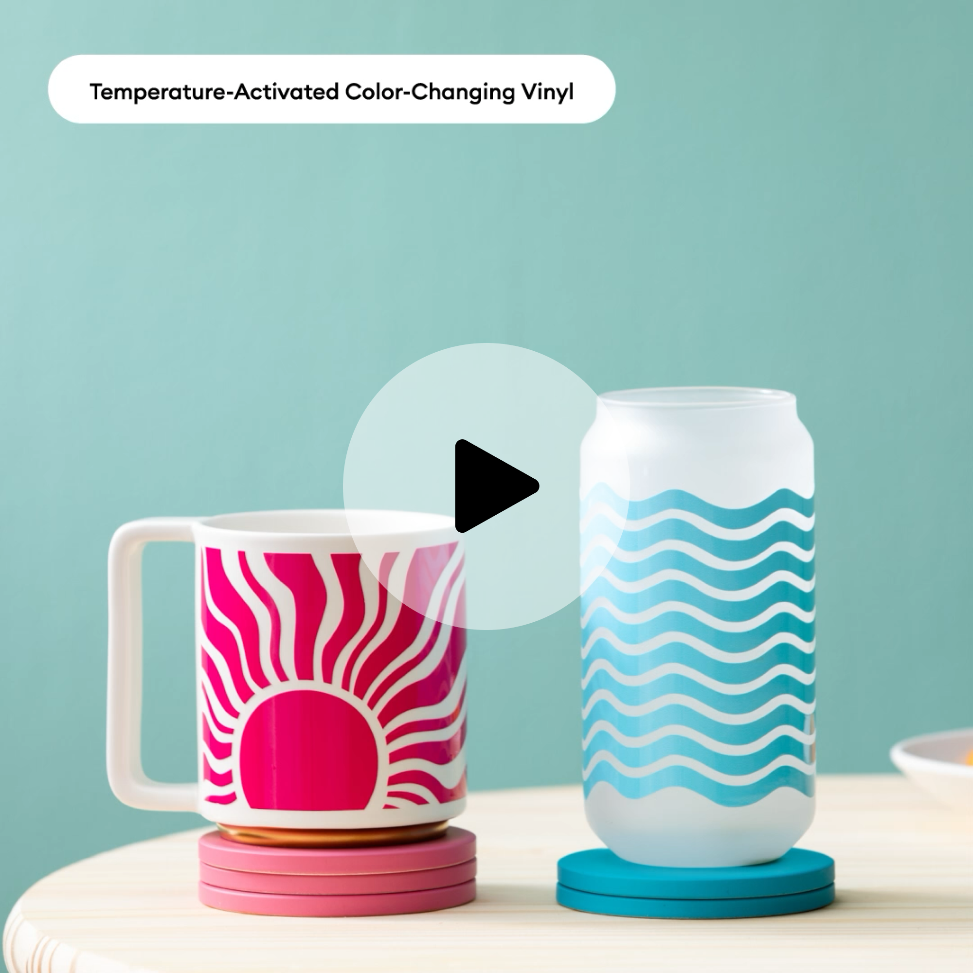Eine Tasse und ein Glas mit Mustern auf Untersetzern. Die Tasse hat ein Sonnendesign. Das Glas hat ein Wellendesign.
