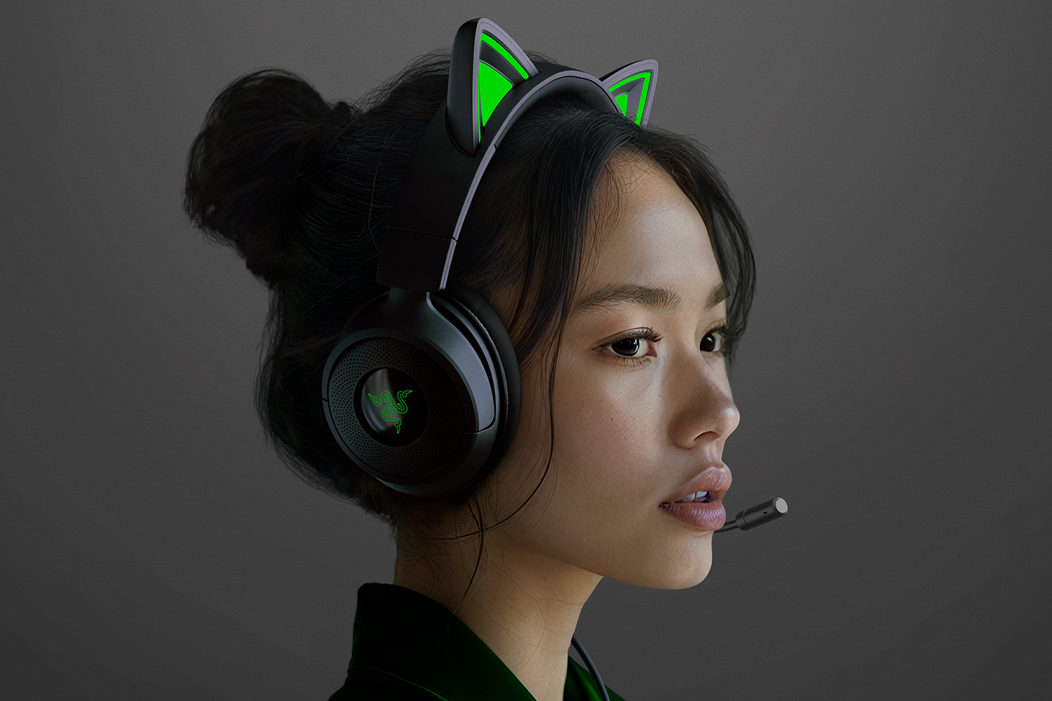 Una donna indossa una cuffia nera con orecchie da gatto. La cuffia ha un microfono e un logo verde. Guarda a destra.