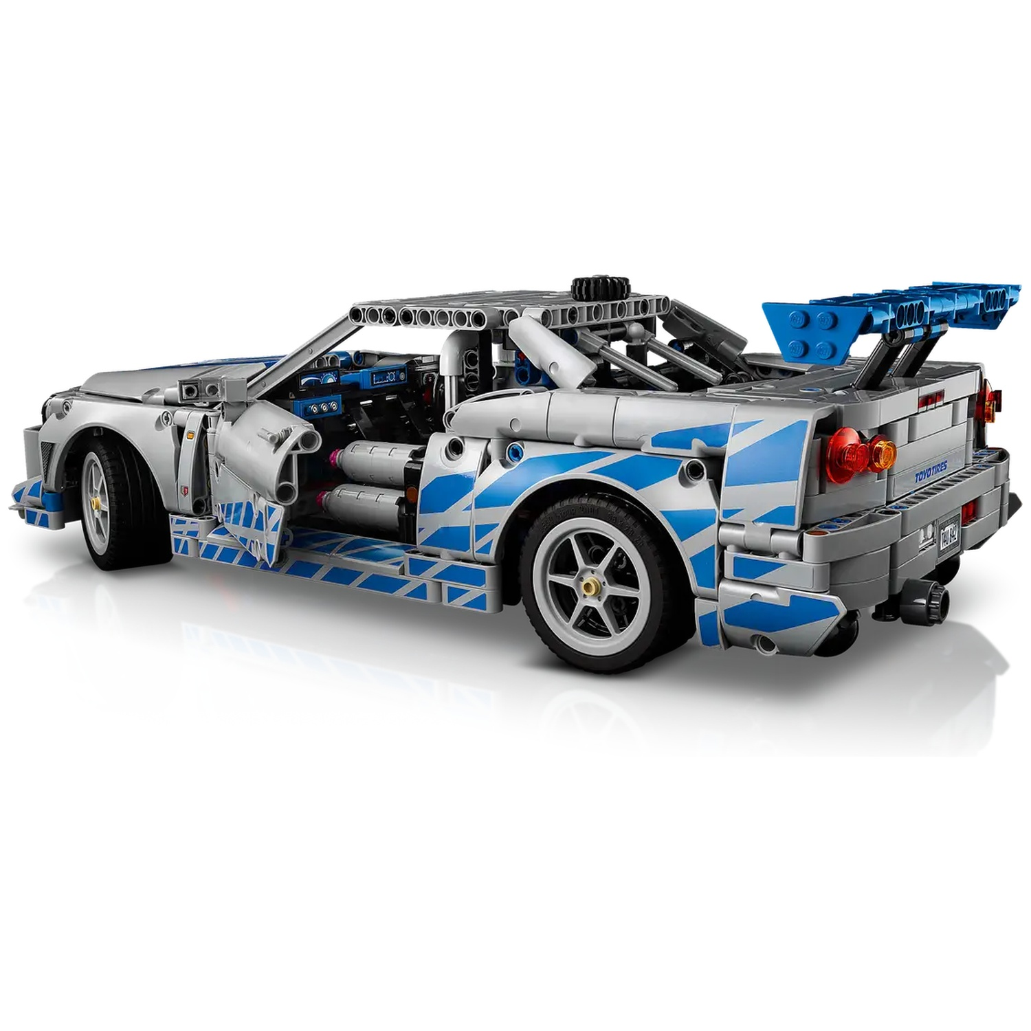 Silver and blue Lego car with a spoiler, open doors, and detailed interior. Wheels are visible. The car is on a white background.