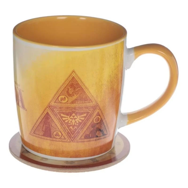 Una taza temática de Zelda con el símbolo de la Trifuerza en un posavasos. La taza es amarilla con un asa blanca.