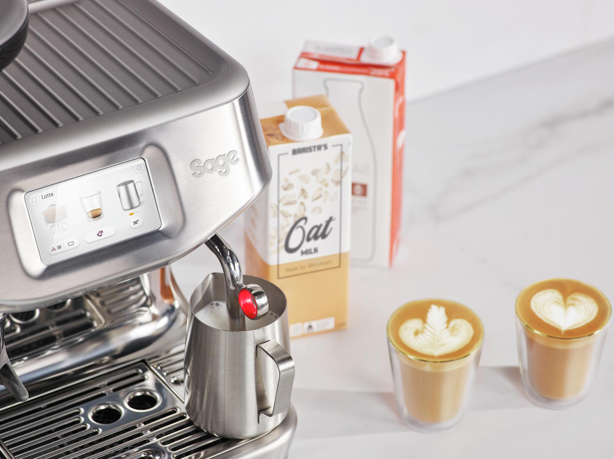 Esspresszógép tejhabosítóval, zabtej kartonnal és két latte art kávéscsészével.
