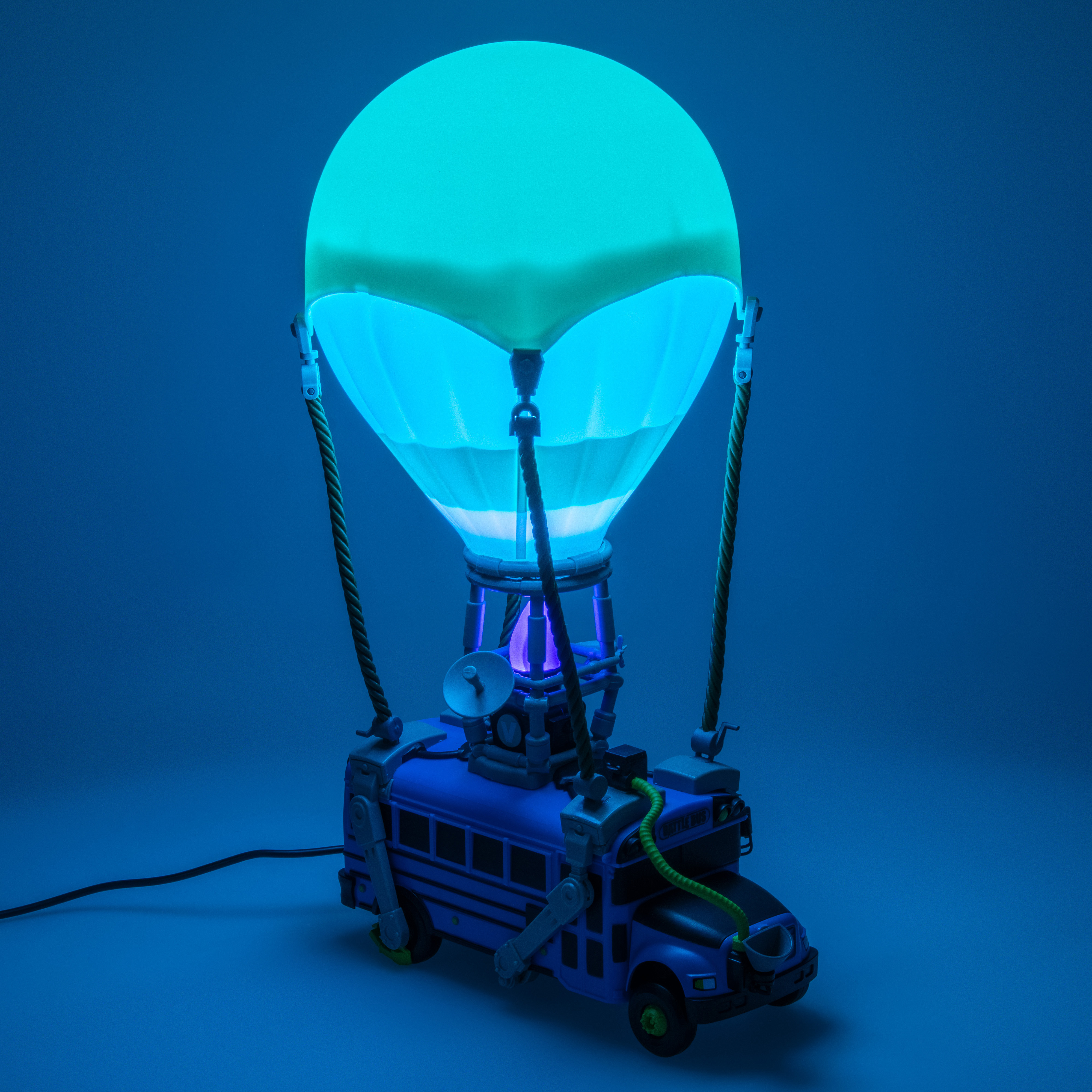 Eine blaue Fortnite Battle Bus-Lampe mit leuchtendem Ballonaufsatz auf blauem Hintergrund.