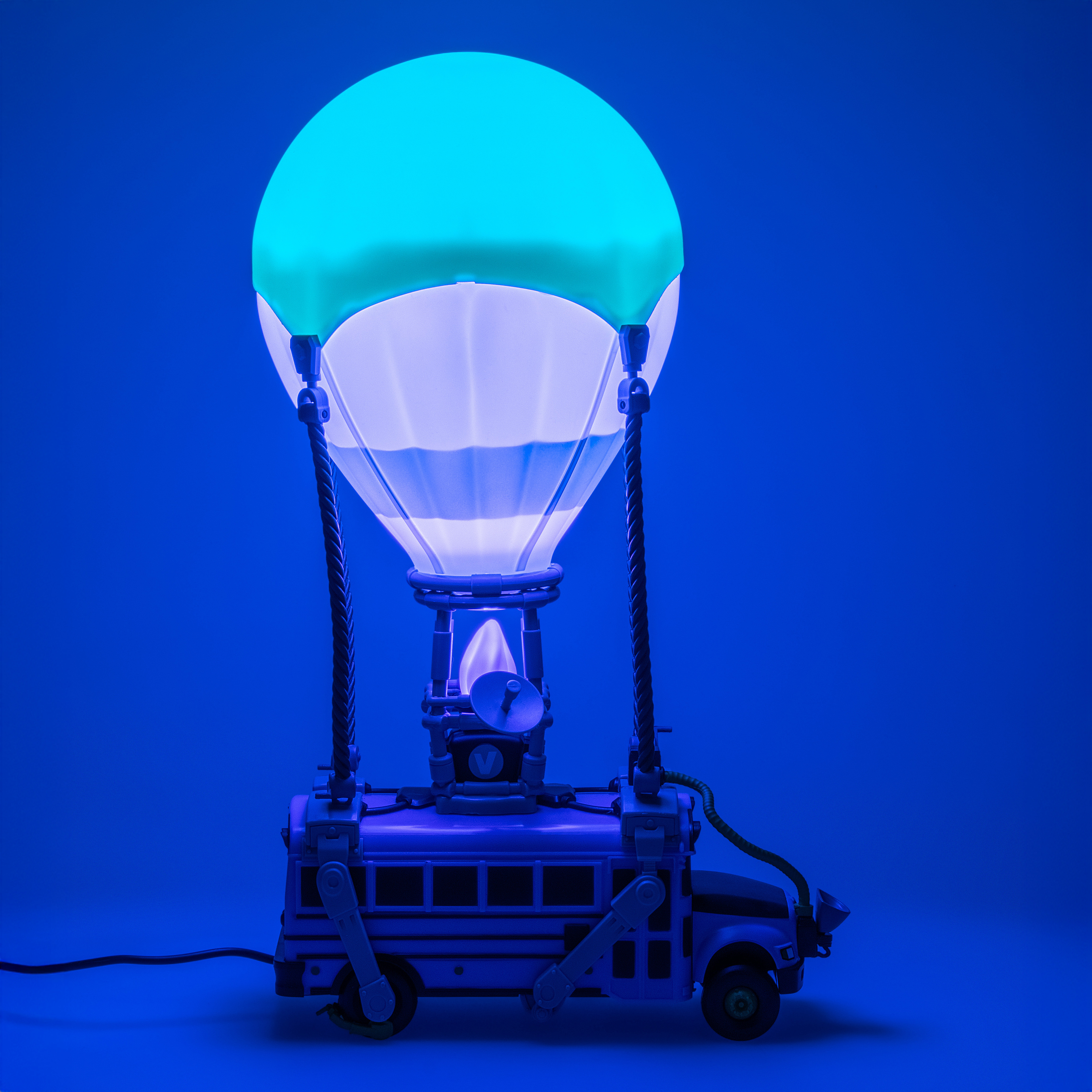 Eine Fortnite Battle Bus-Lampe leuchtet blau. Sie hat einen Heißluftballon oben. Der Hintergrund ist einfarbig blau.