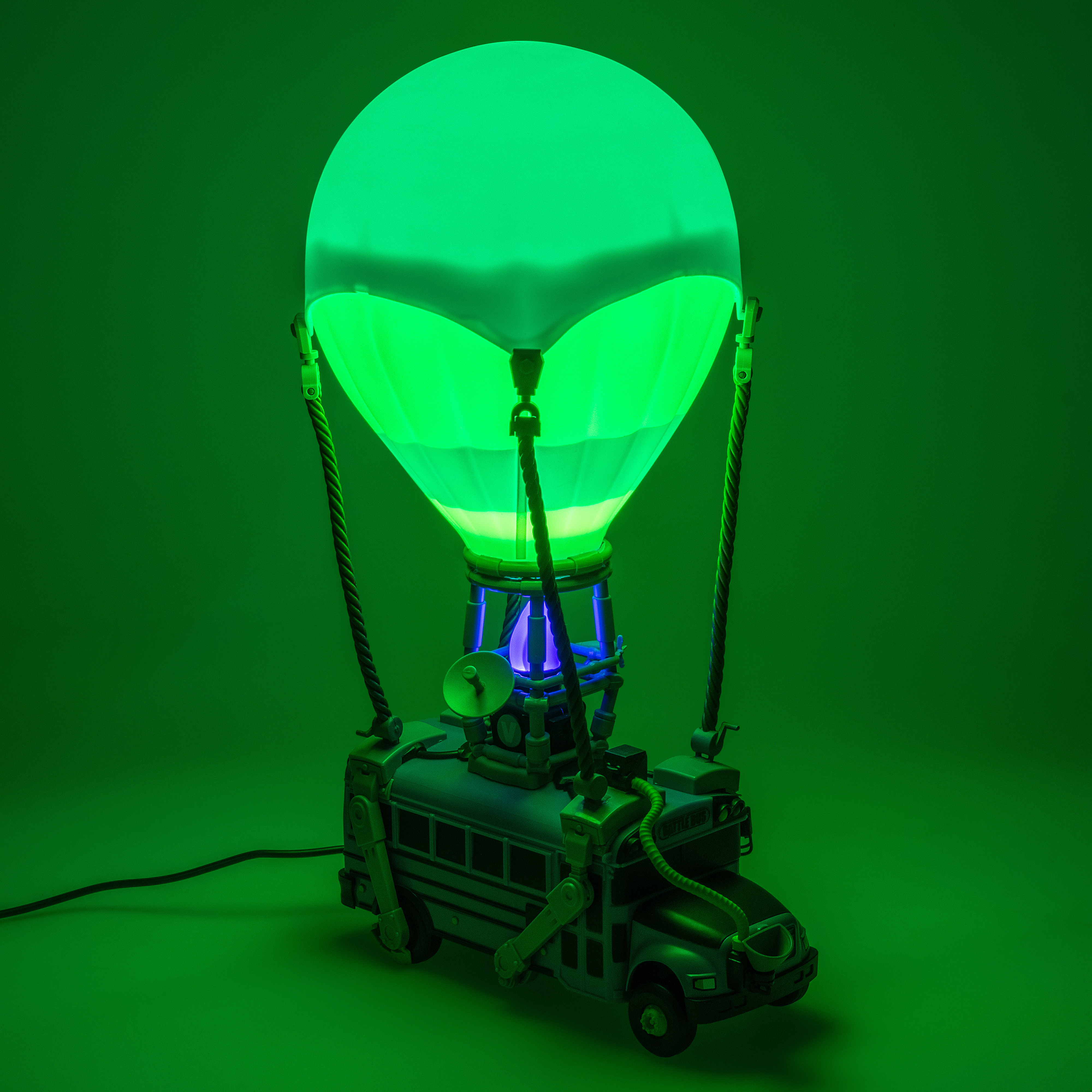 Eine Lampe in Form eines Heißluftballons mit Busbasis, alles in Grün. Der Ballon leuchtet.