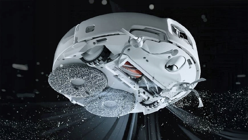 Biały robot odkurzający, widok od dołu. Widoczne są dwie okrągłe szczotki. Tło jest ciemne z cząsteczkami.