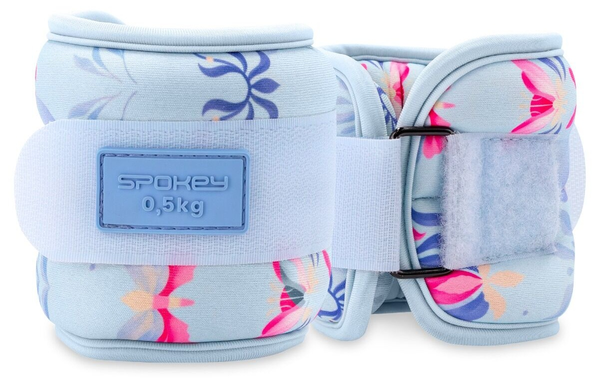 Dwa jasnoniebieskie obciążniki na kostki Spokey z kwiatowymi wzorami. Każdy ma pasek na rzep i wagę 0,5 kg.