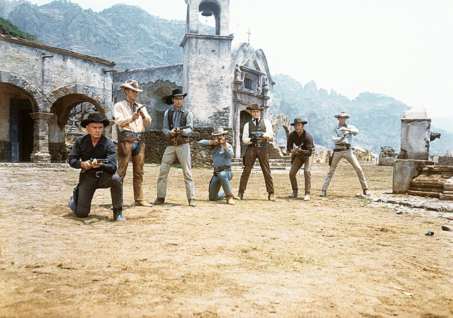 Sieben Cowboys in Westernkleidung stehen und knien in einem staubigen Gebiet und halten Waffen. Im Hintergrund befindet sich ein Kirchengebäude.