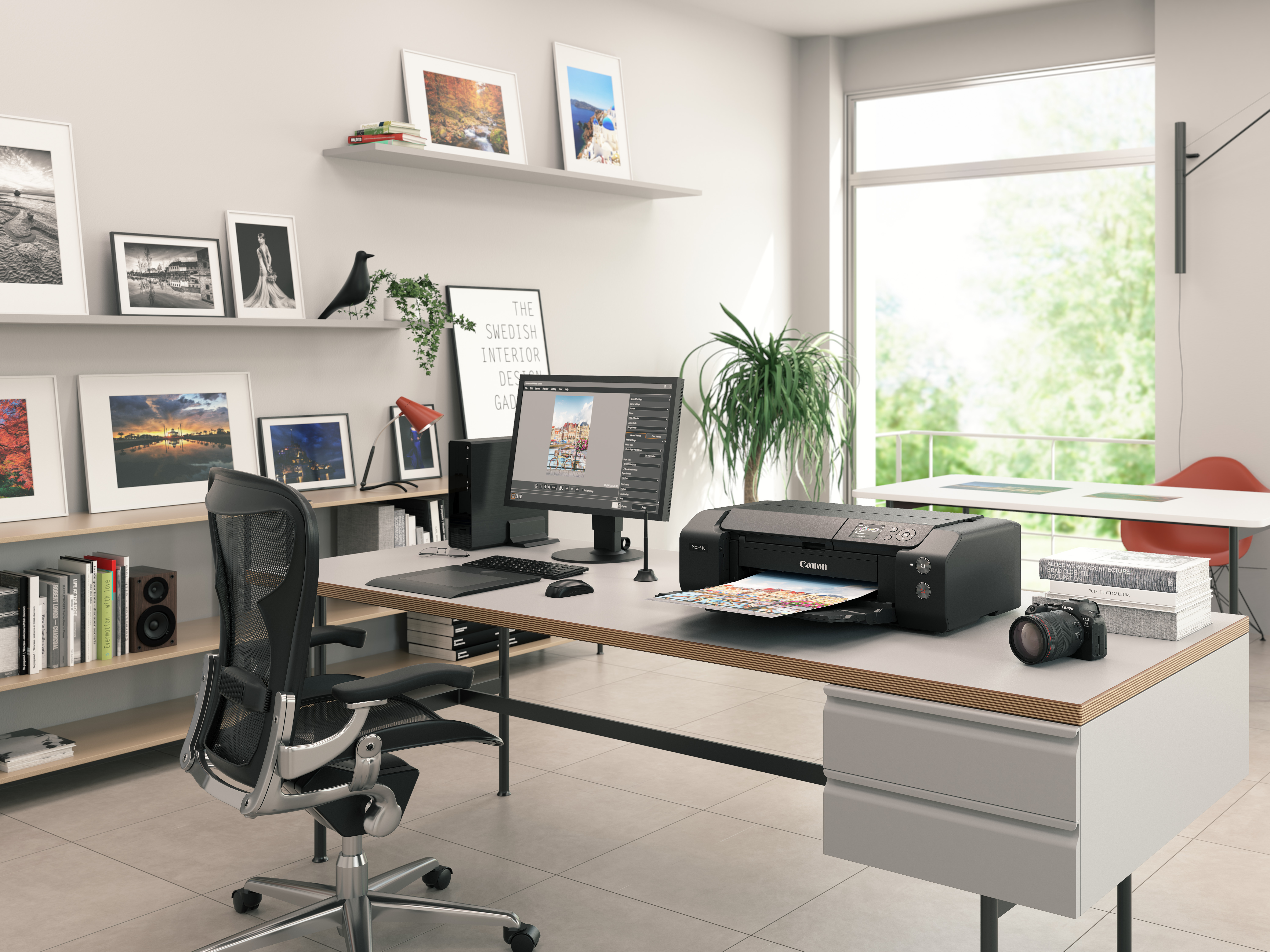Büro mit Schreibtisch, Drucker, Monitor mit Bild, gerahmten Fotos, Kamera, Stuhl und Fenster mit Aussicht.