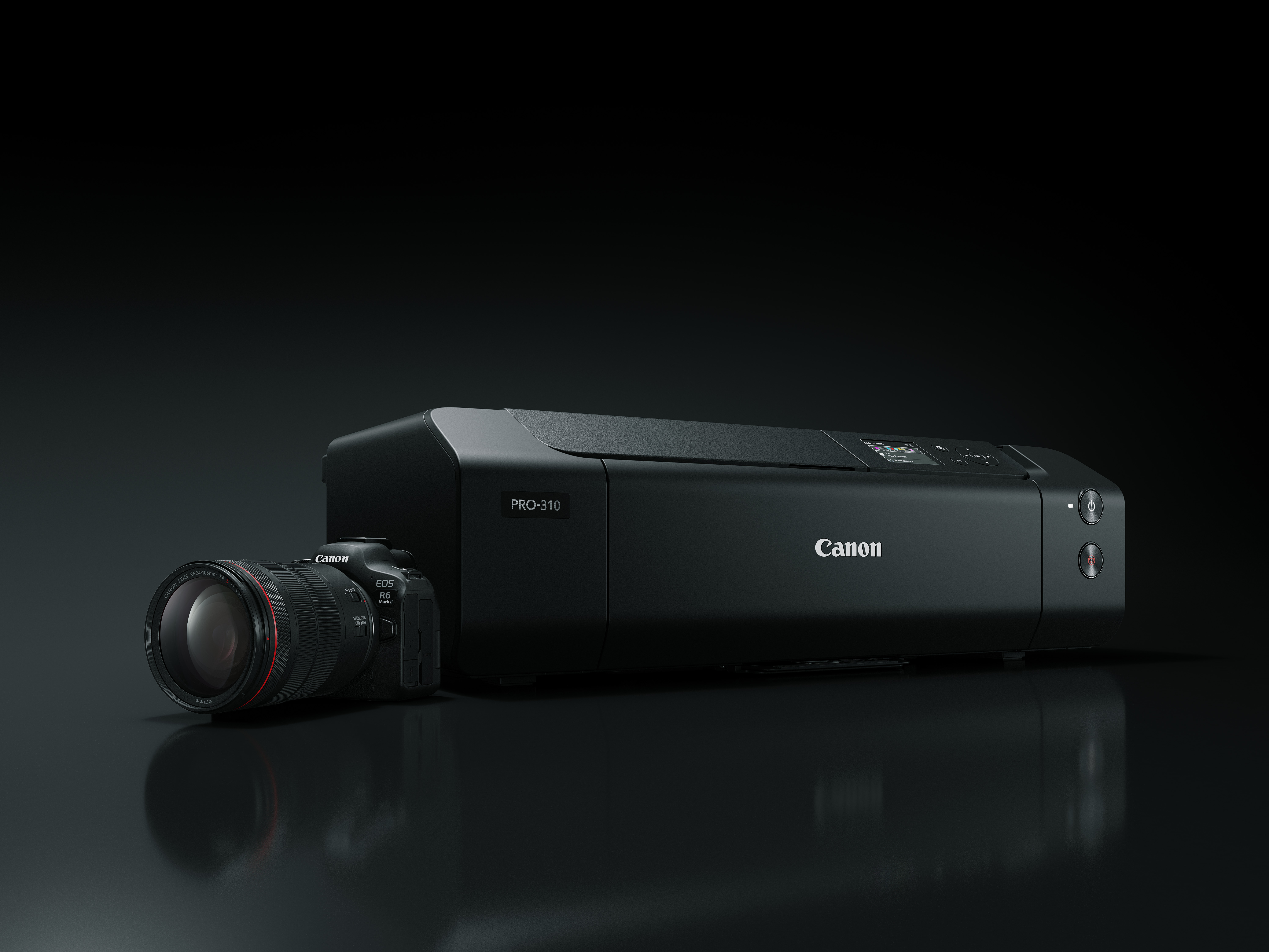 Ein schwarzer Canon PRO-310 Drucker mit einer Canon EOS R6 Kamera und Objektiv auf schwarzer Oberfläche.