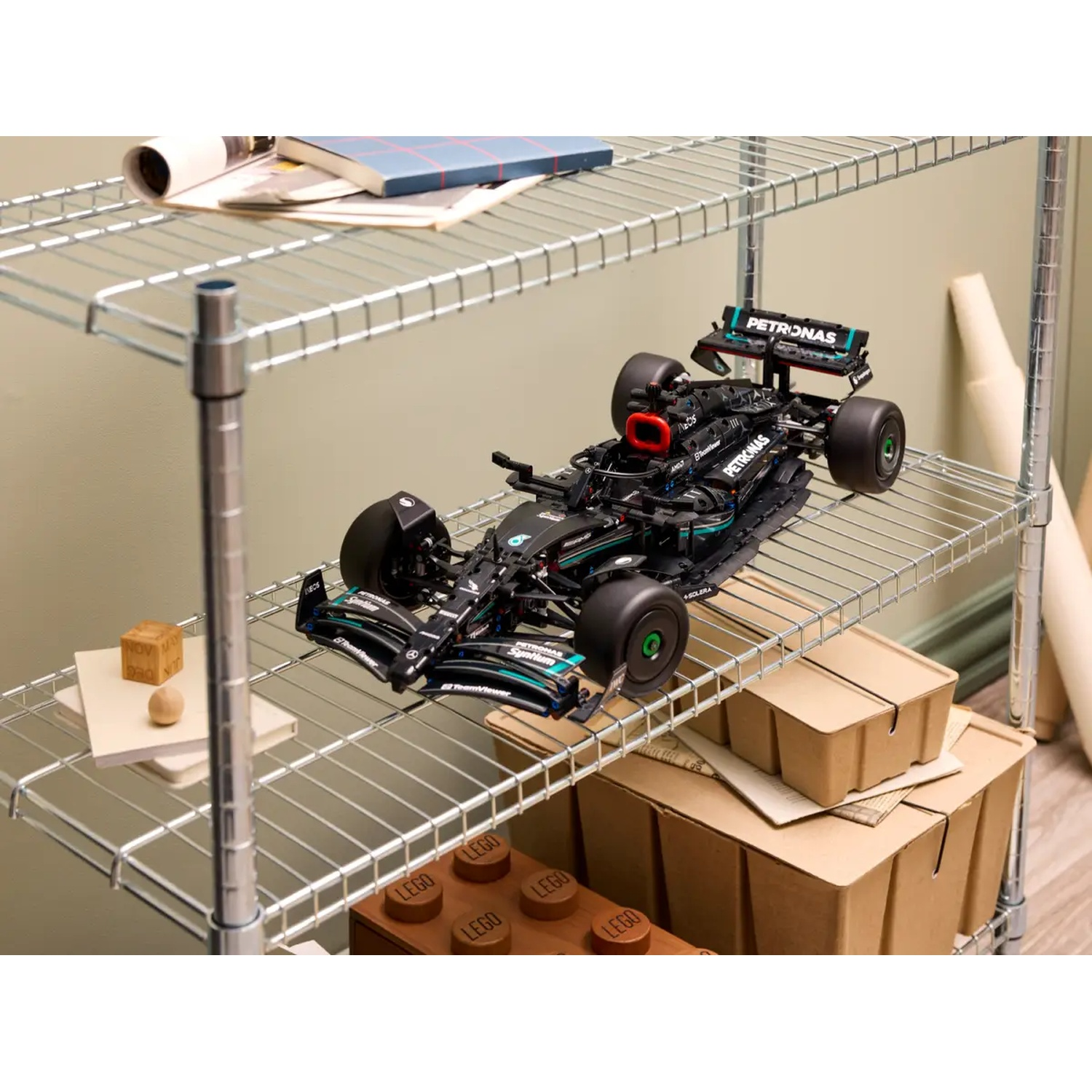 Un modèle de voiture Lego F1 Petronas noir est sur une étagère. D'autres articles incluent des boîtes, des blocs Lego et des livres.