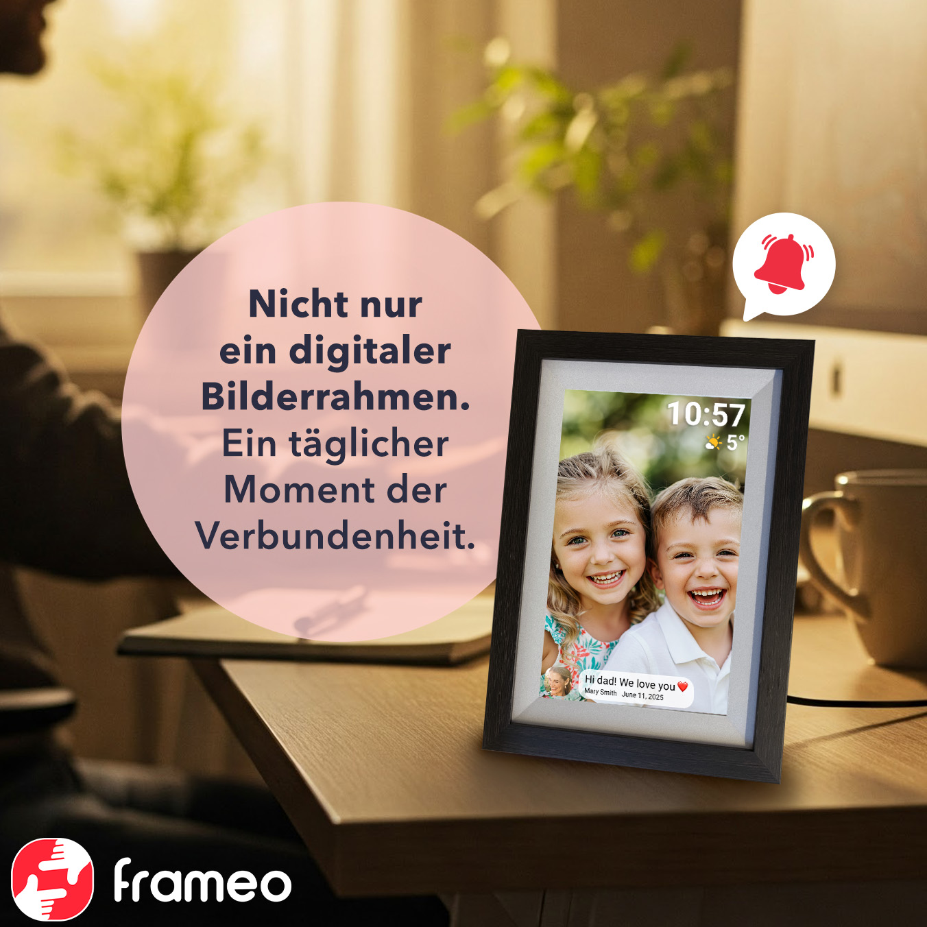Ein digitaler Fotorahmen zeigt zwei lächelnde Kinder. Text sagt: 'Hallo Papa! Wir lieben dich'. Eine Benachrichtigungsglocke ist zu sehen.