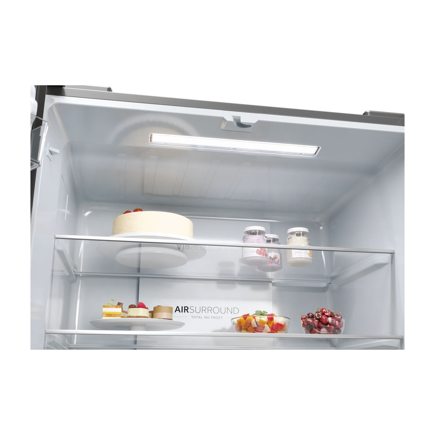 All'interno di un frigorifero: torta, dessert, frutta e ciliegie. Ripiani con frontali in vetro. Interno bianco e illuminazione a LED.