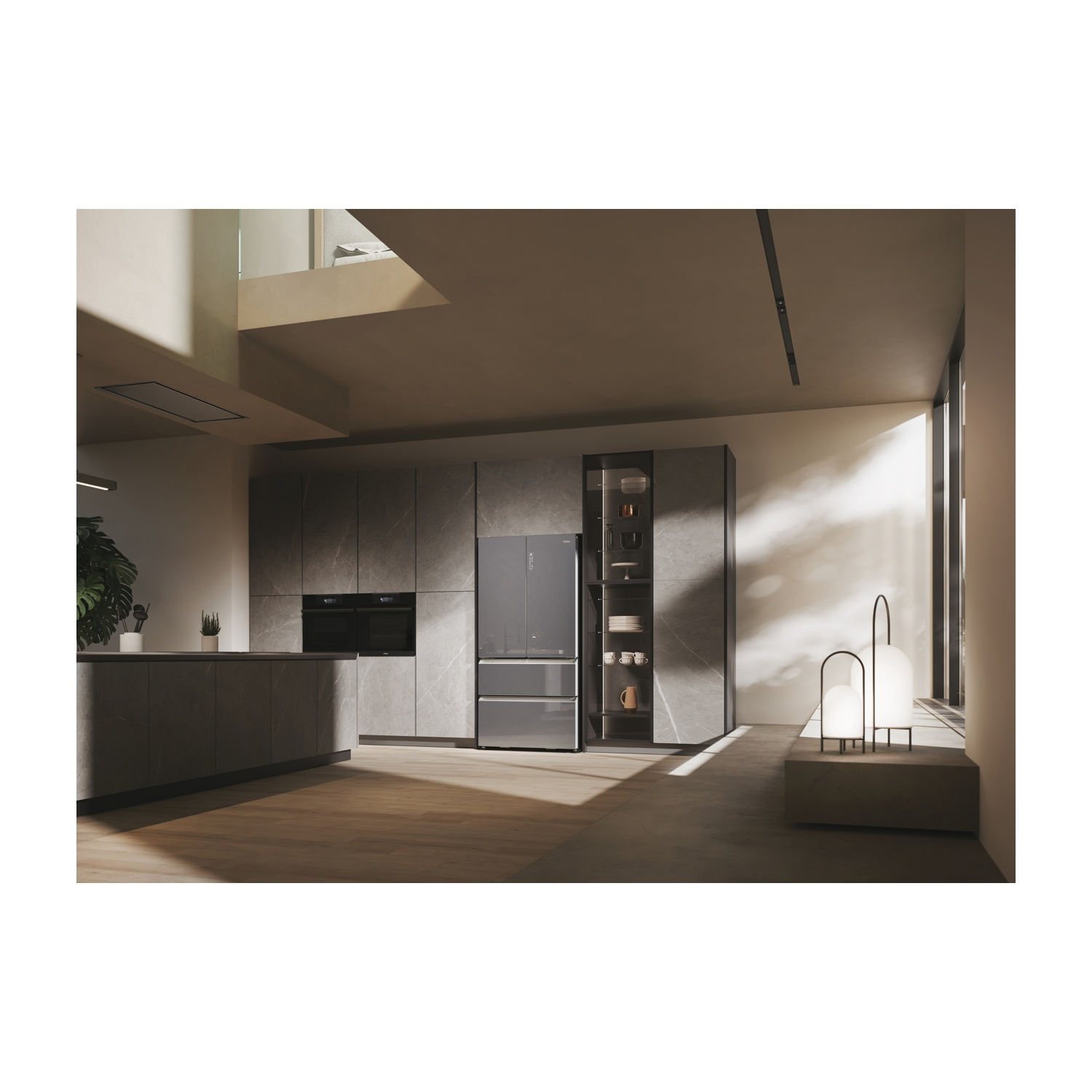Una cucina moderna con frigorifero, forni e armadi. La luce naturale inonda lo spazio. Sullo sfondo si vede una scala.