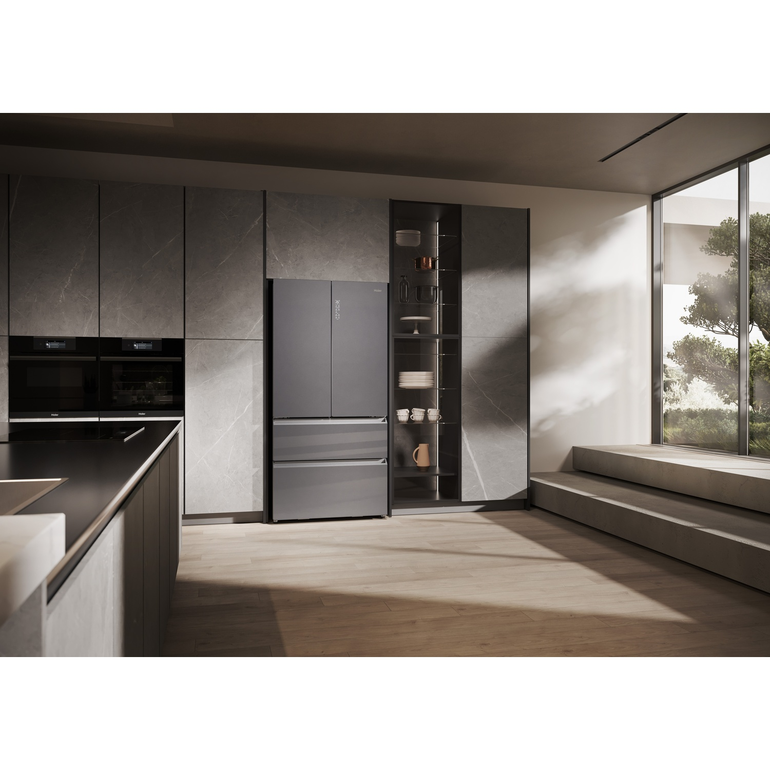 Una cucina moderna con frigorifero grigio, forni a incasso e vetrina. Grande finestra sul giardino.