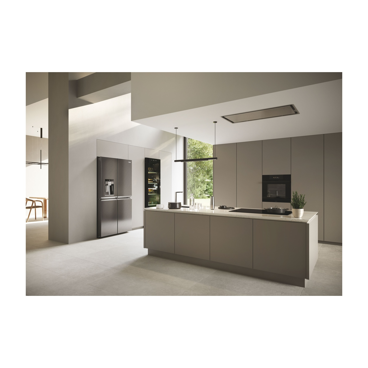 Cucina moderna con mobili grigi, isola, frigorifero e forno a incasso. Luce naturale e lampade a sospensione.