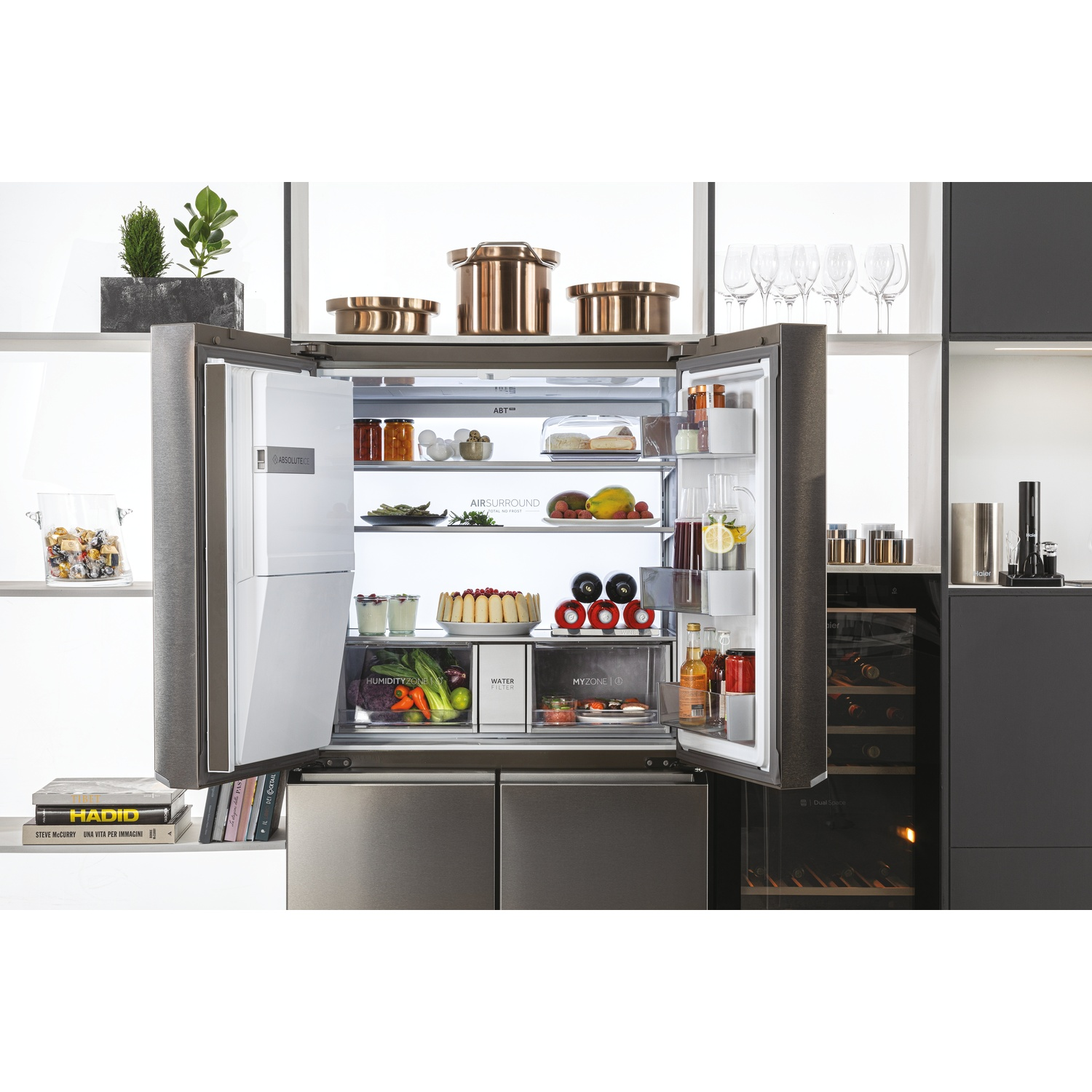 Frigorifero aperto che mostra generi alimentari, una cantinetta e utensili da cucina. Mensole con libri e piante decorative. Design contemporaneo.