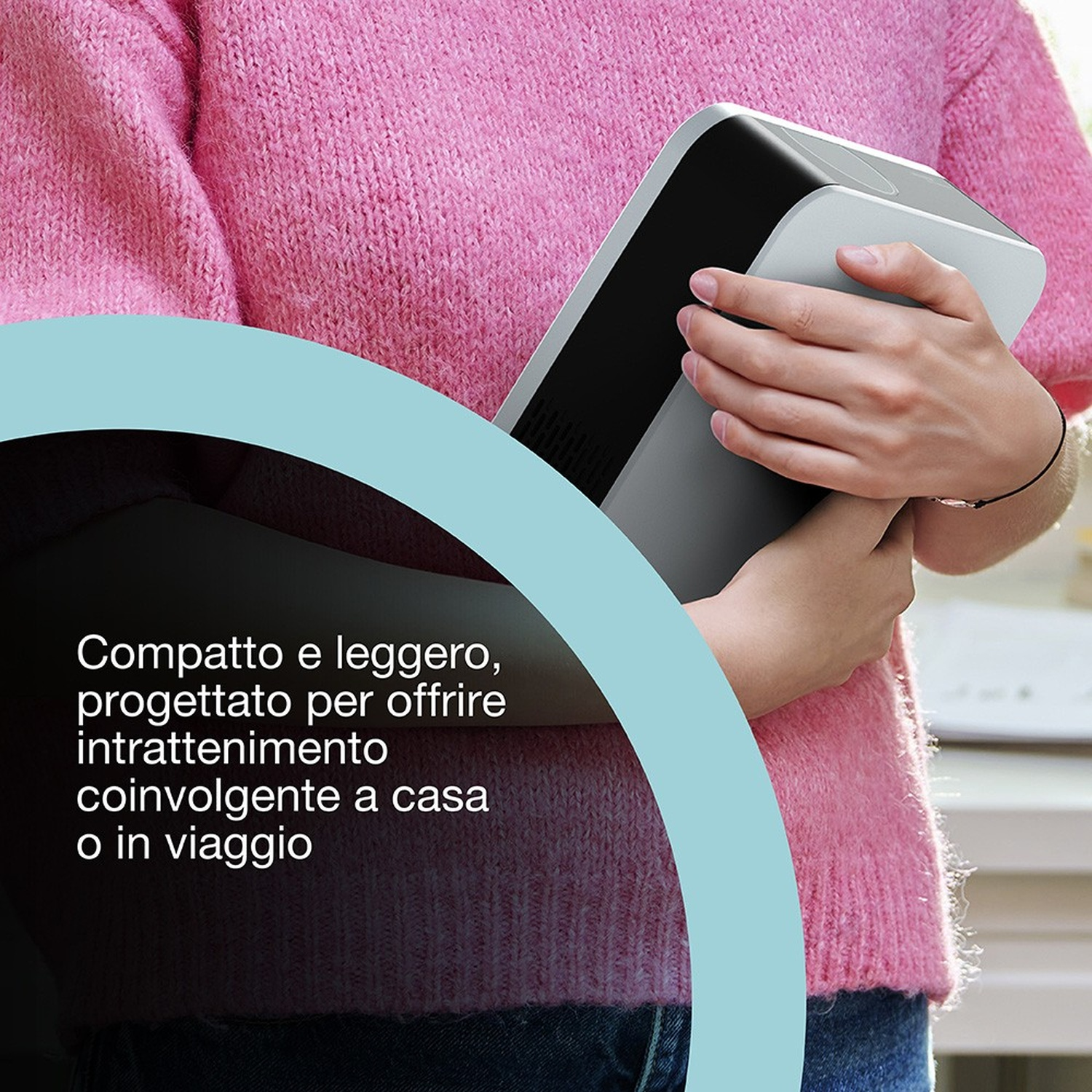 Una persona tiene in mano un dispositivo grigio con una parte superiore nera, indossando un maglione rosa. Il testo recita: Compatto e leggero.
