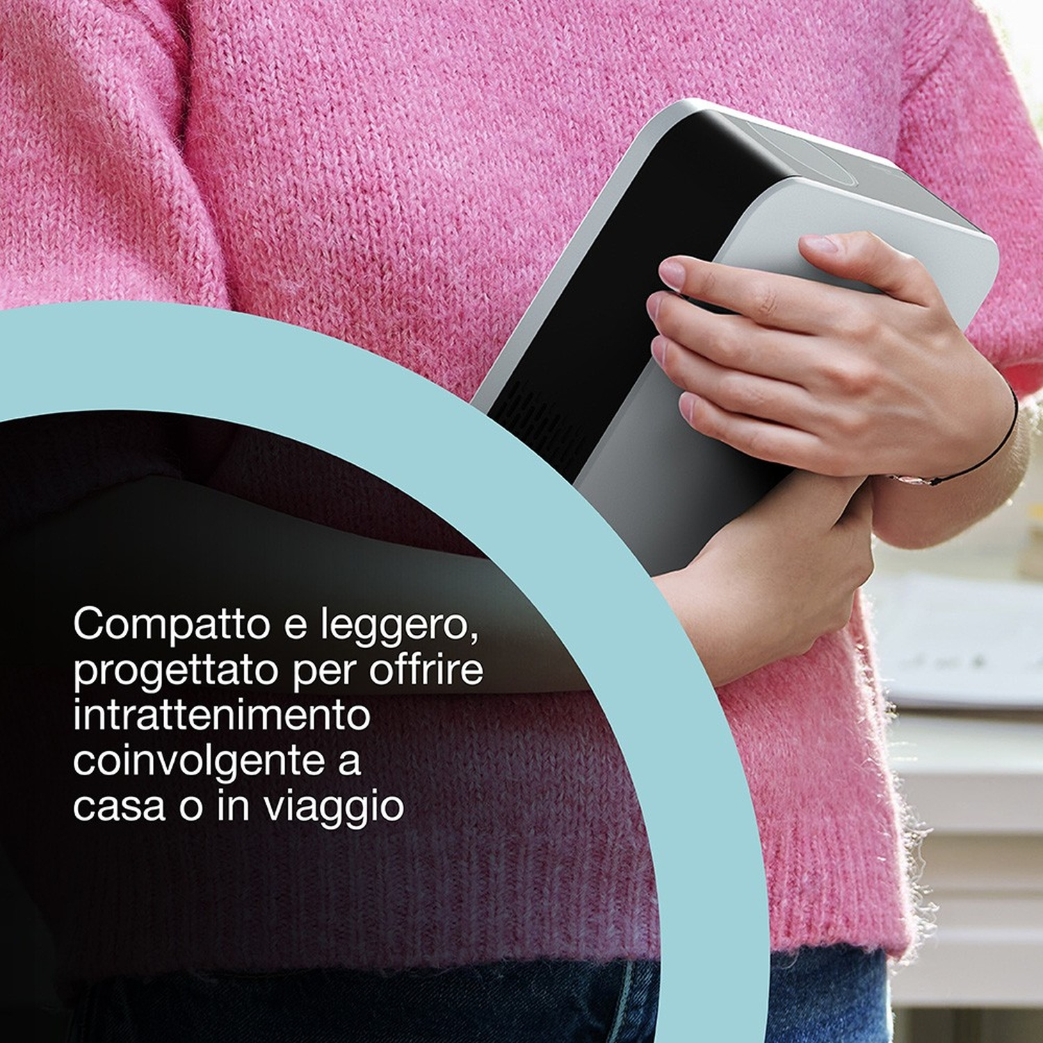 Una persona con un maglione rosa tiene in mano un dispositivo grigio e nero. Il testo in italiano è a sinistra.