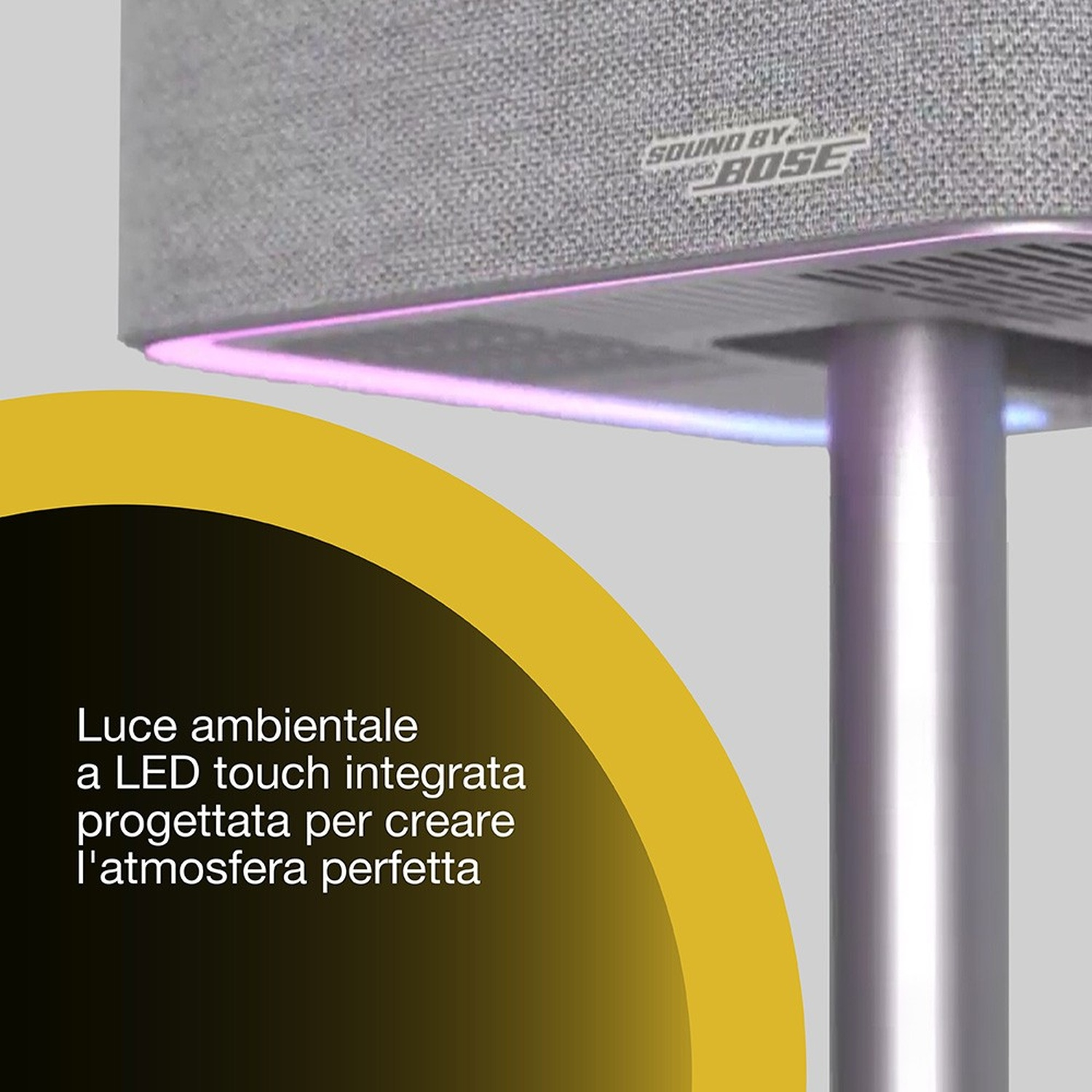 Un altoparlante grigio con il logo Bose ha una striscia luminosa nella parte inferiore. Una curva gialla è a sinistra.