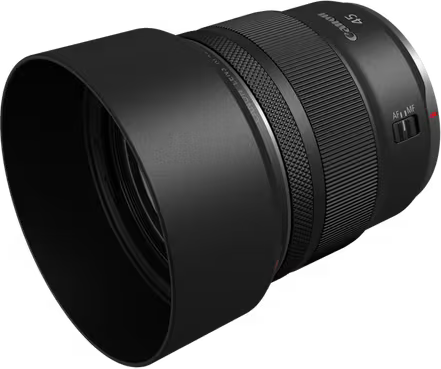 Ein schwarzes Canon-Objektiv mit Gegenlichtblende liegt auf einer schwarzen Oberfläche. Das Objektiv hat Fokus- und Zoomringe.