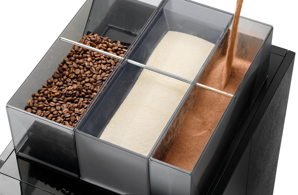 Kaffeebohnen, weißes Pulver und braunes Pulver befinden sich in durchsichtigen Behältern. Braunes Pulver wird in seinen Behälter gegossen.
