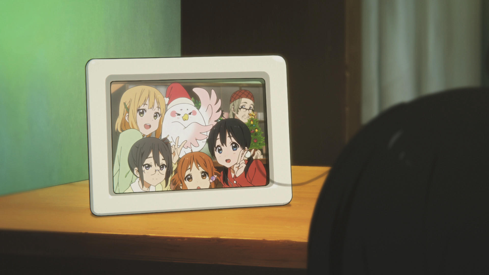 Foto im Anime-Stil in einem Rahmen. Gruppe von Charakteren posiert mit einem Vogel. Weihnachtsbaum im Hintergrund.