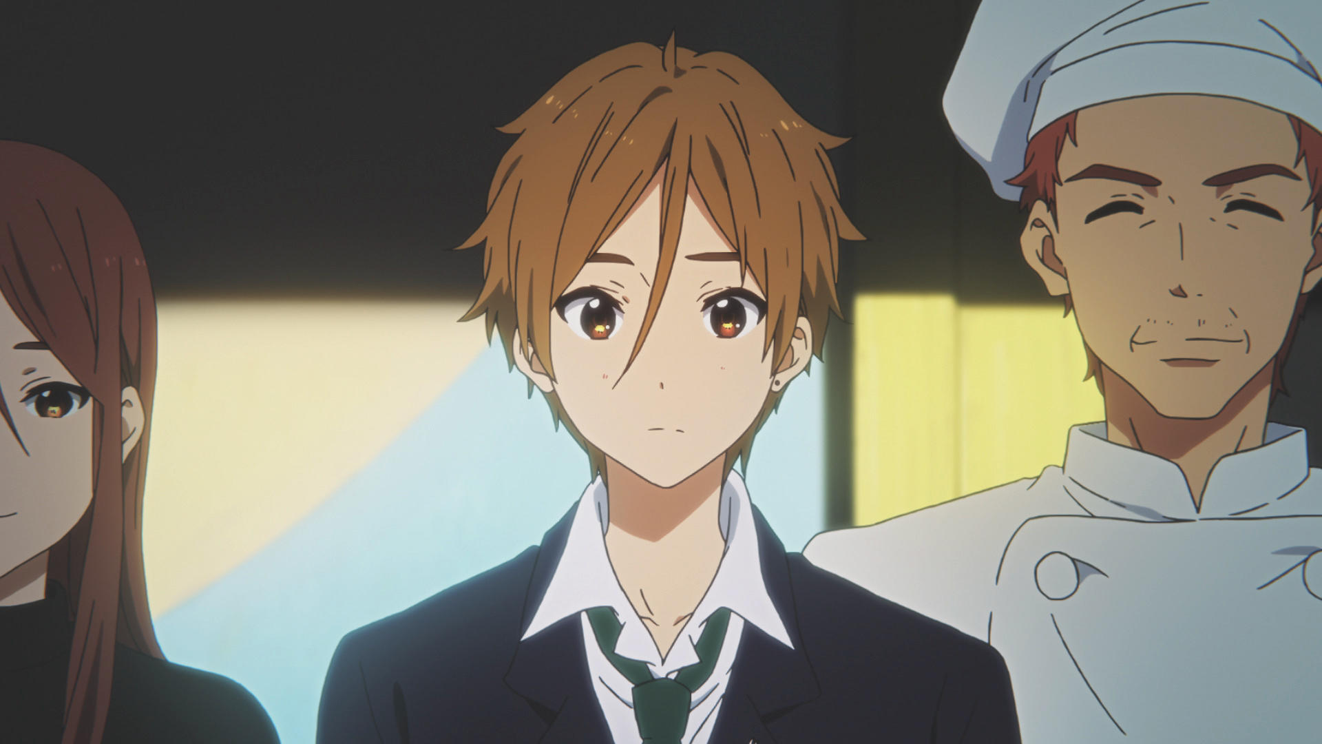 Anime-Bild von drei Personen. Ein junger Mann mit braunen Haaren und Anzug steht zwischen einer Frau und einem Koch.
