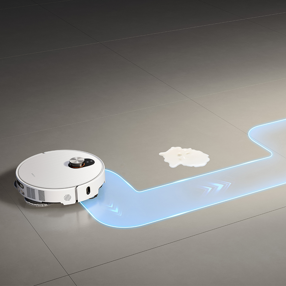 Un aspirateur robot blanc nettoie un sol. Un chemin bleu indique l'itinéraire de nettoyage et un déversement de lait est sur le sol.