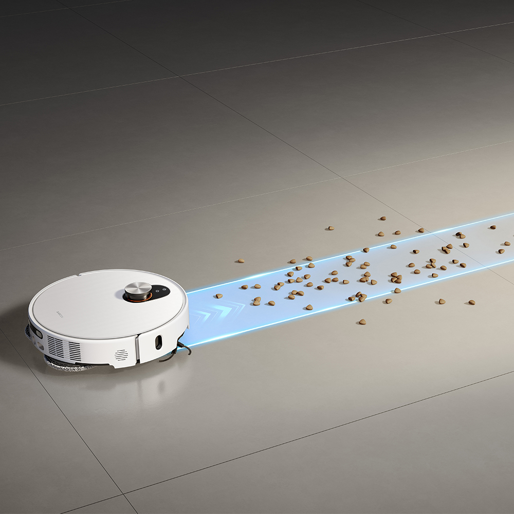 Un aspirateur robot blanc nettoie un sol carrelé gris, ramassant des débris. Une trace lumineuse bleue indique le chemin de nettoyage.
