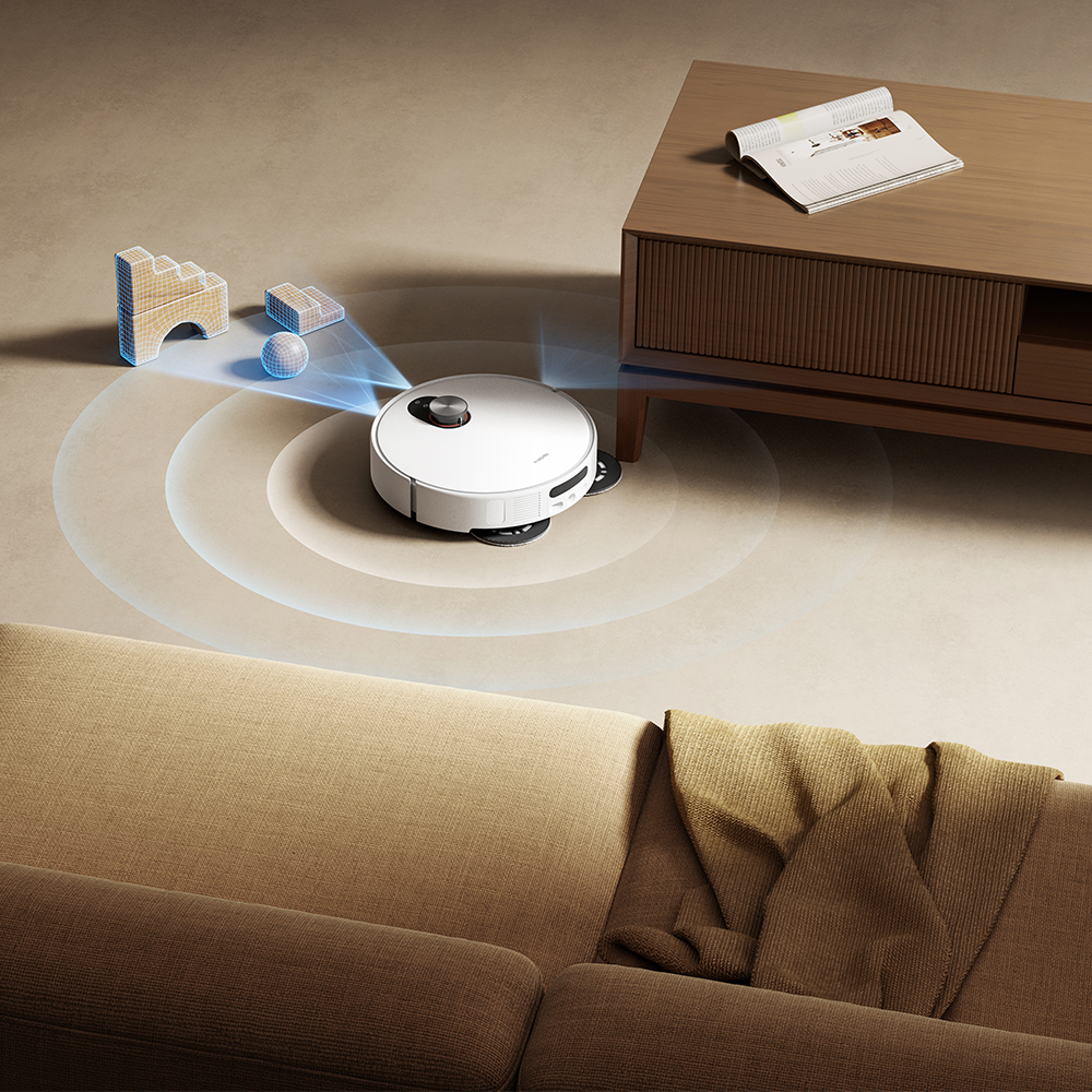 Un aspirateur robot blanc nettoie un salon. Un canapé, une table basse et des objets sont en arrière-plan.