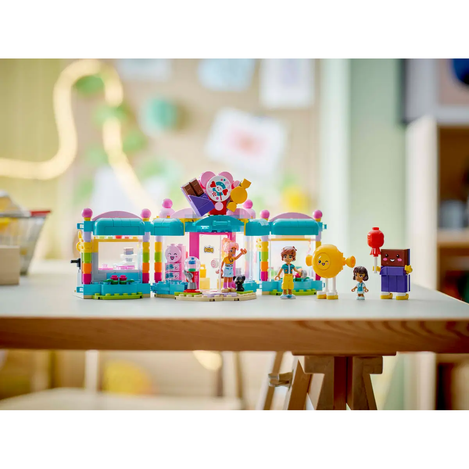 Lego Friends set on a table. Includes a colorful building, various figurines, and other Lego accessories.