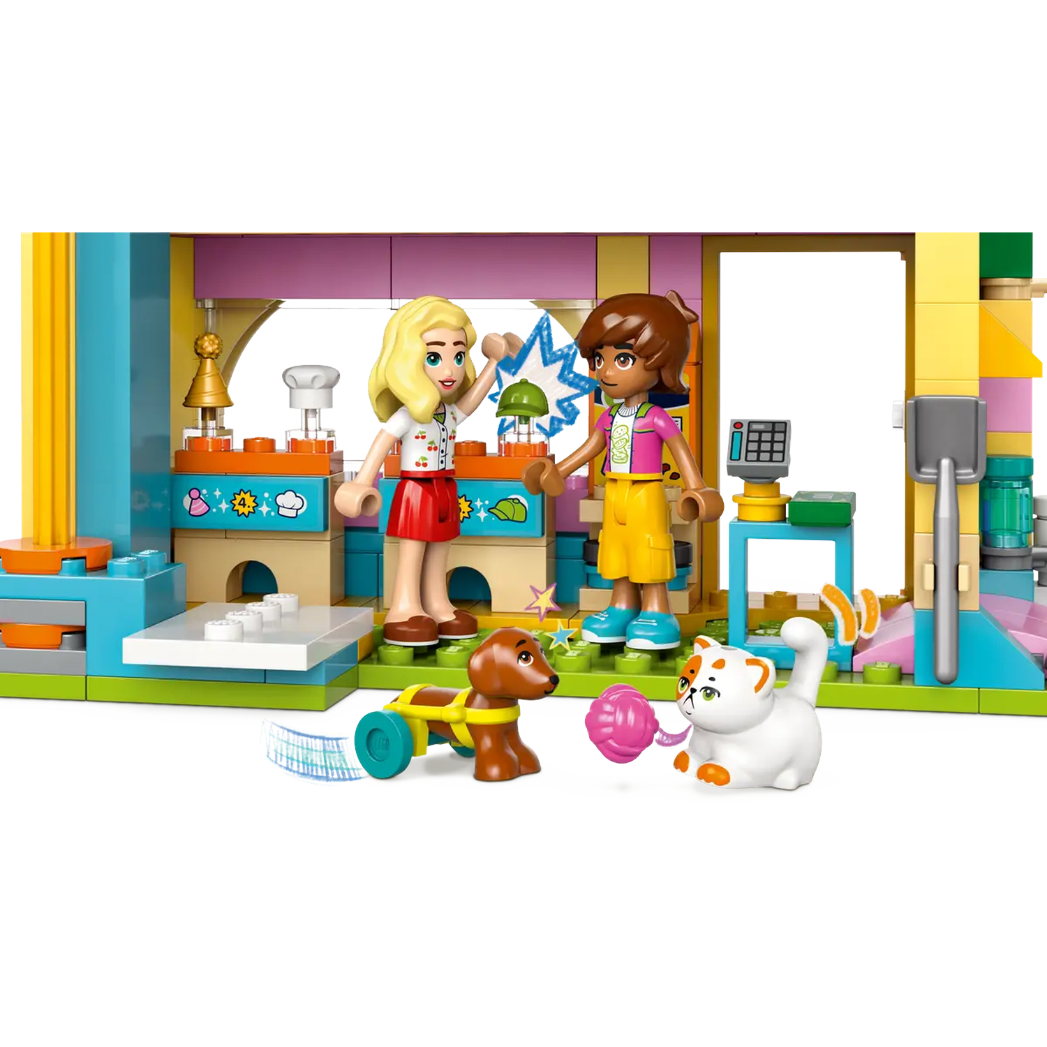 Lego set with two girls, a dog in a cart, and a cat playing. The scene takes place in a colorful building.