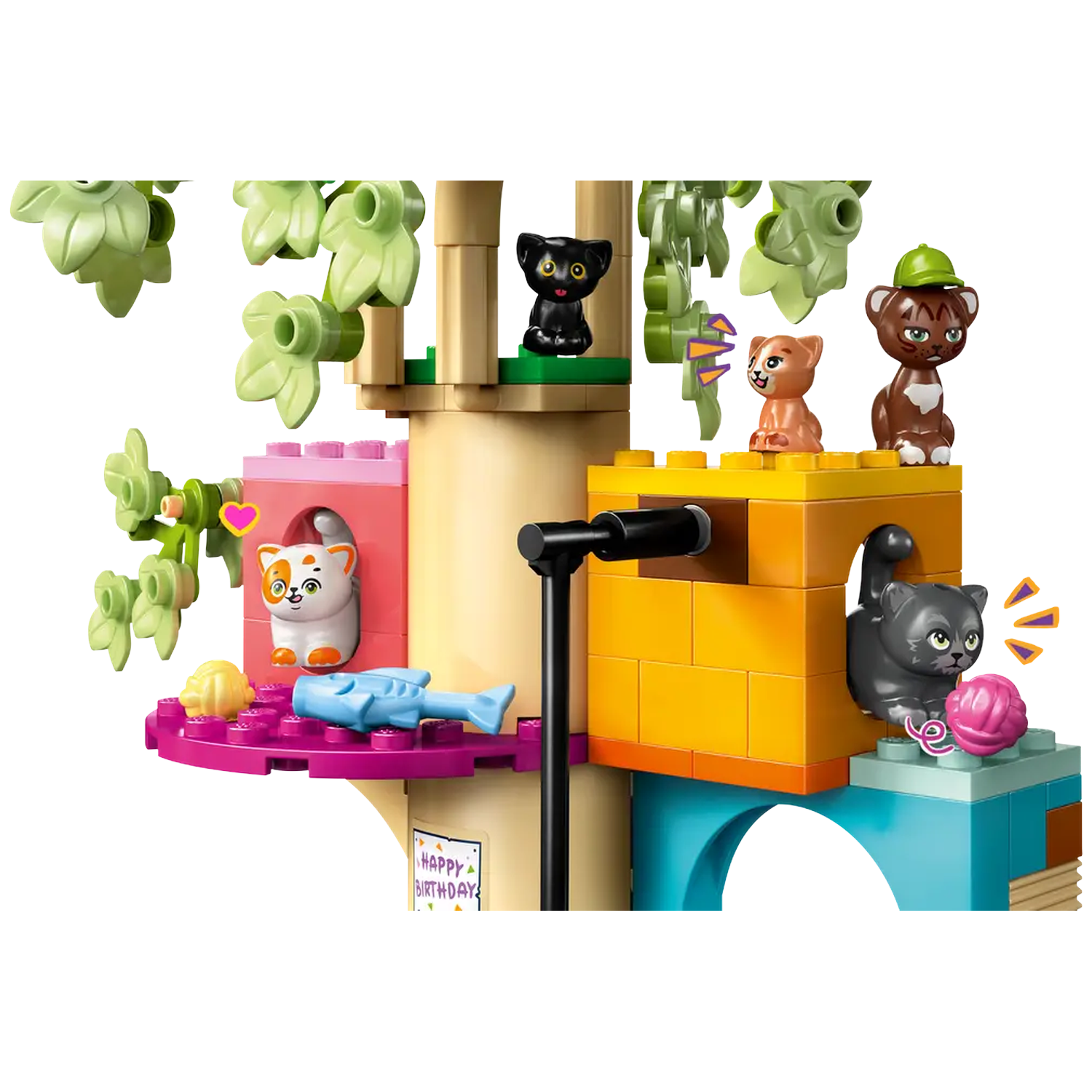 A Lego set with several cat figures. The set includes a treehouse with colorful blocks, a fish, and a ball of yarn.