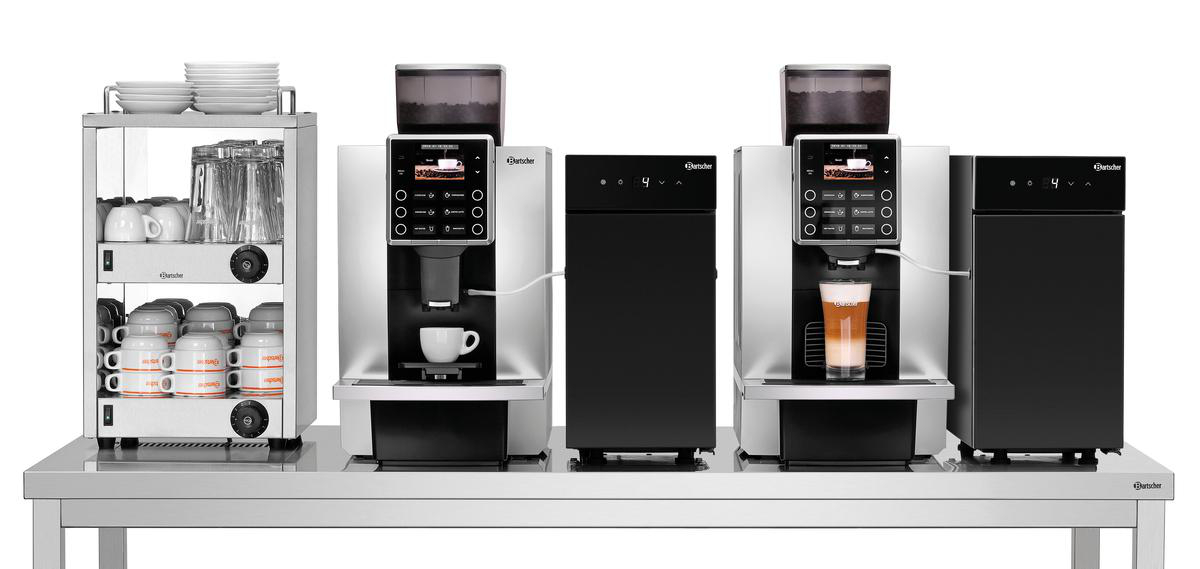 Kaffeemaschinen und ein Tassenwärmer auf einem Metalltisch. Eine Maschine macht Latte. Weiße Tassen und Teller sind sichtbar.