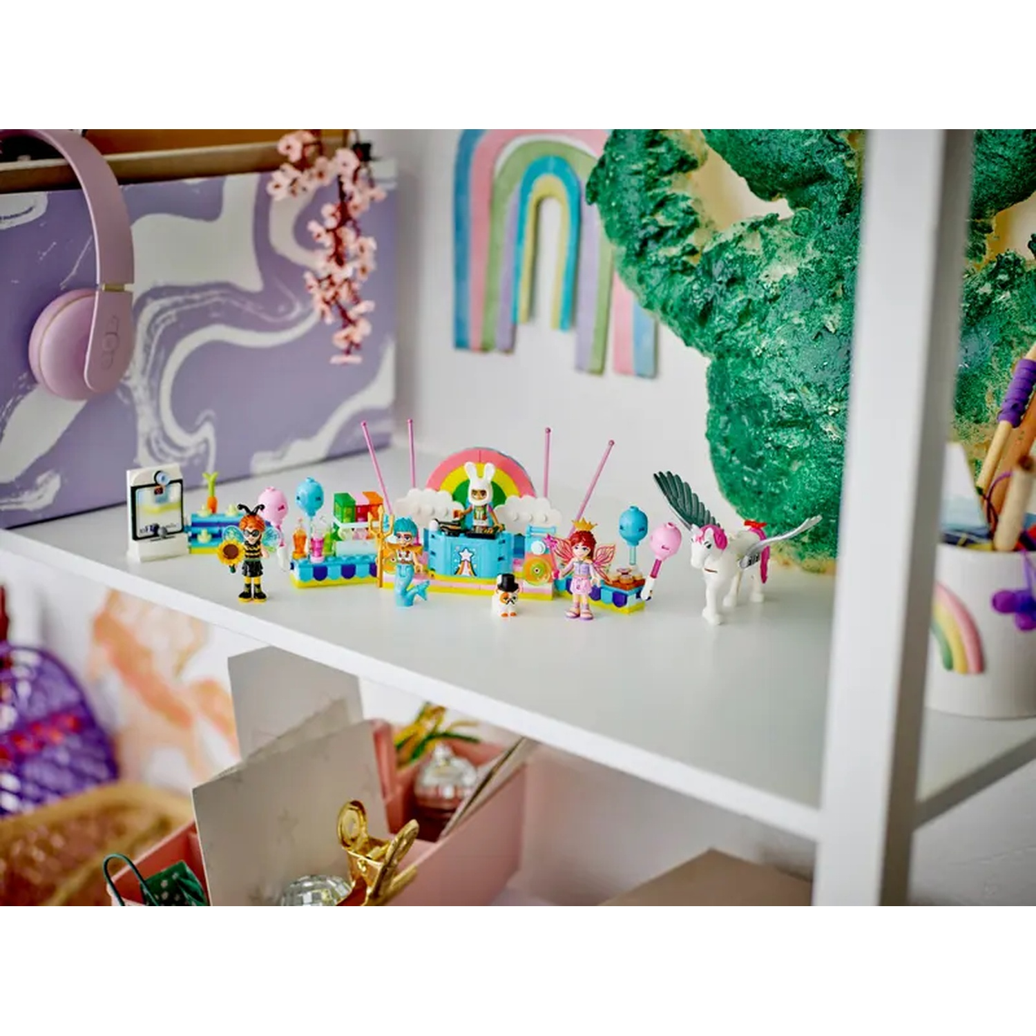 A shelf with toys including Lego figures, a unicorn, and a mini-carnival set. A pair of headphones and a cactus decoration.