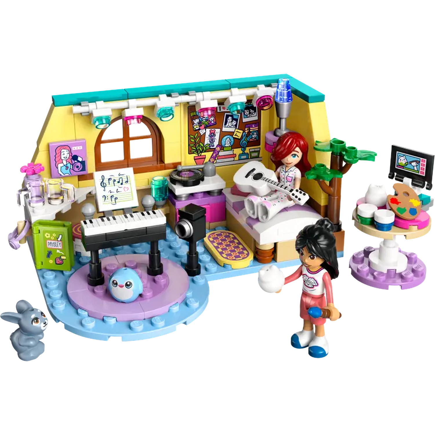Ensemble Lego représentant une pièce avec deux personnages, une guitare, un clavier et du matériel d'art. Un lapin et un pingouin sont également présents.