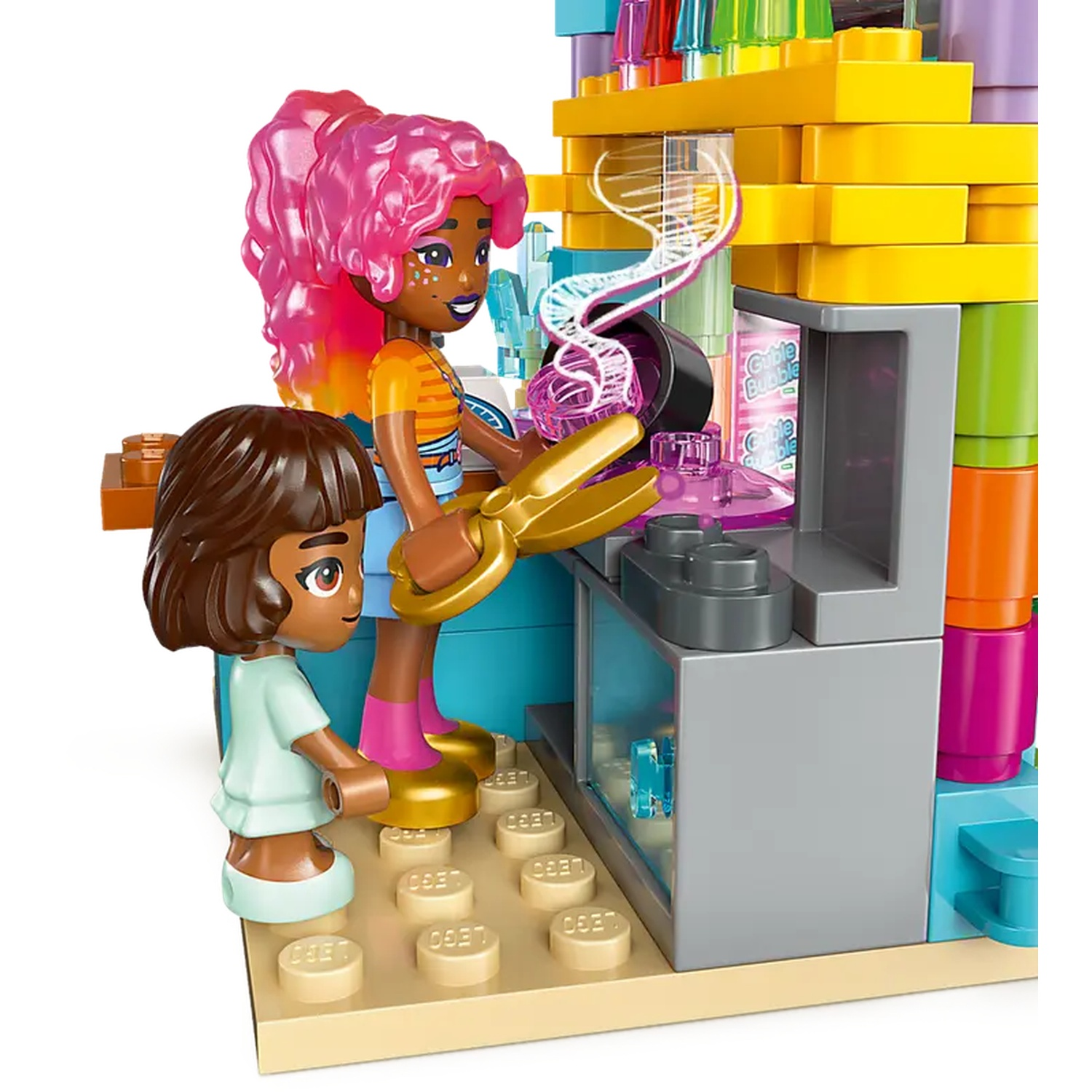 Two Lego figures with pink hair and brown hair are in a colorful Lego structure. One figure holds gold scissors.