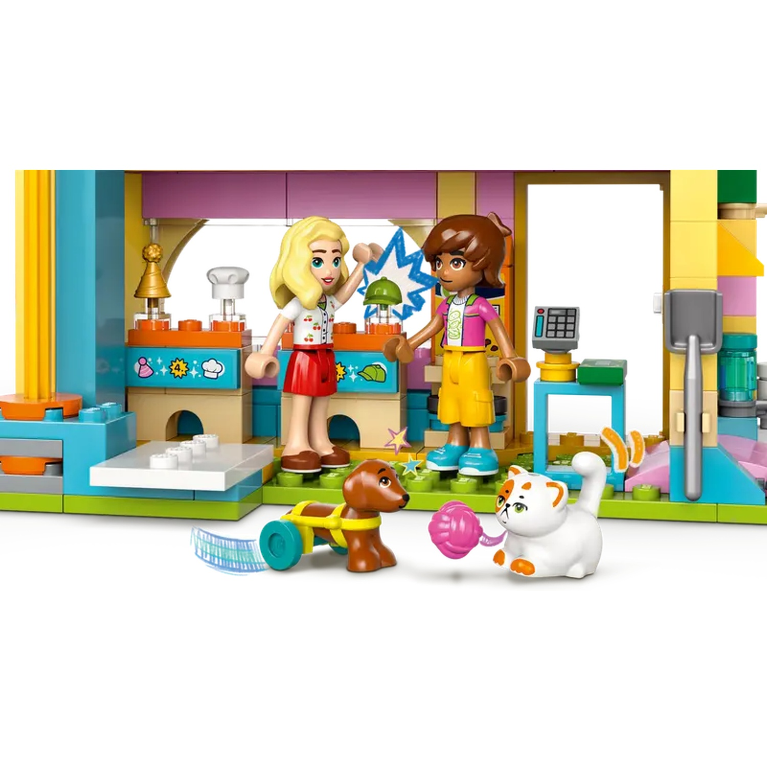 Two Lego figures with a dog and a cat in a kitchen setting. One figure holds a lightning bolt. A pink ball is near the cat.