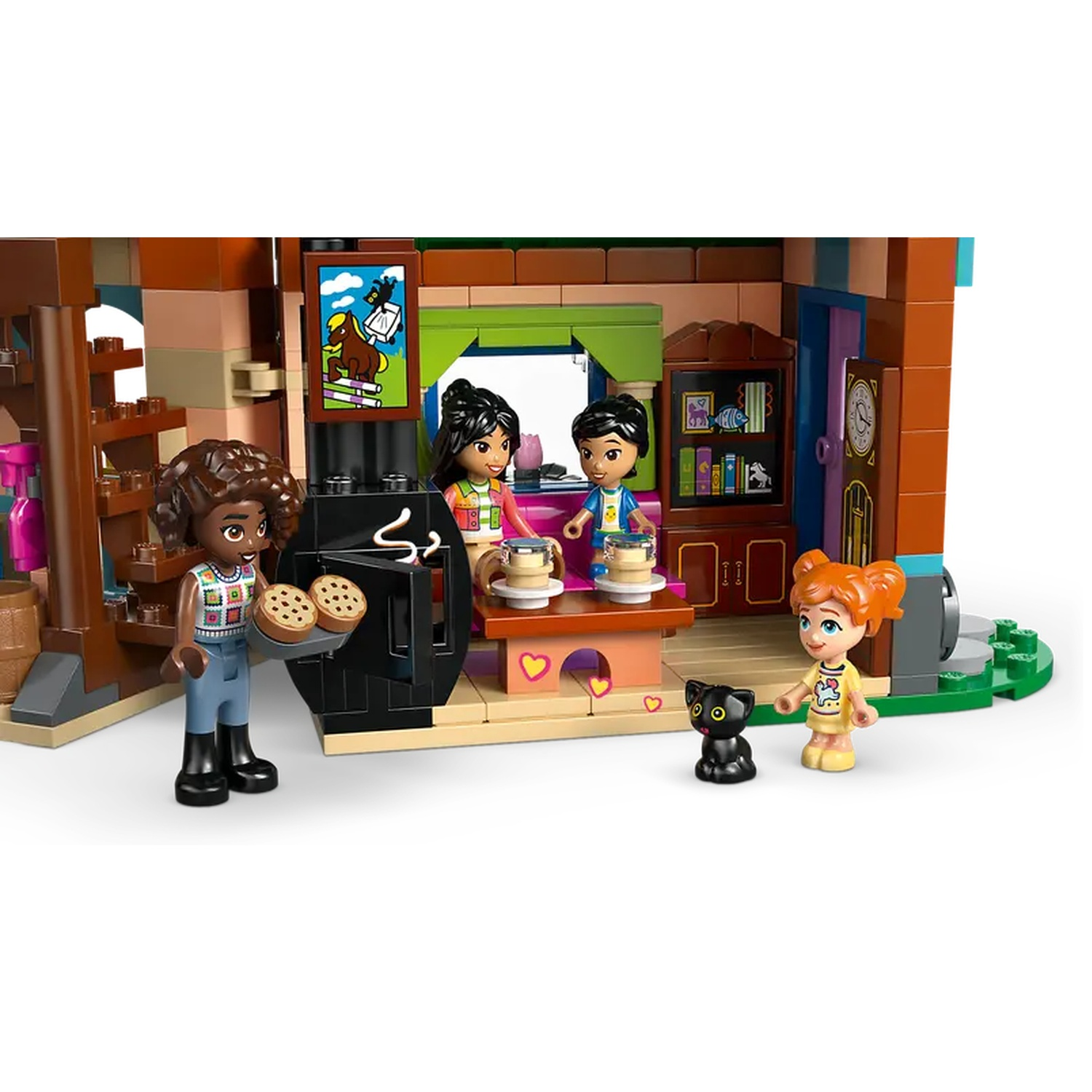 Lego Friends set. Een meisje houdt koekjes vast. Twee andere meisjes staan bij een tafel met kopjes. Een meisje met een kat staat in de buurt.